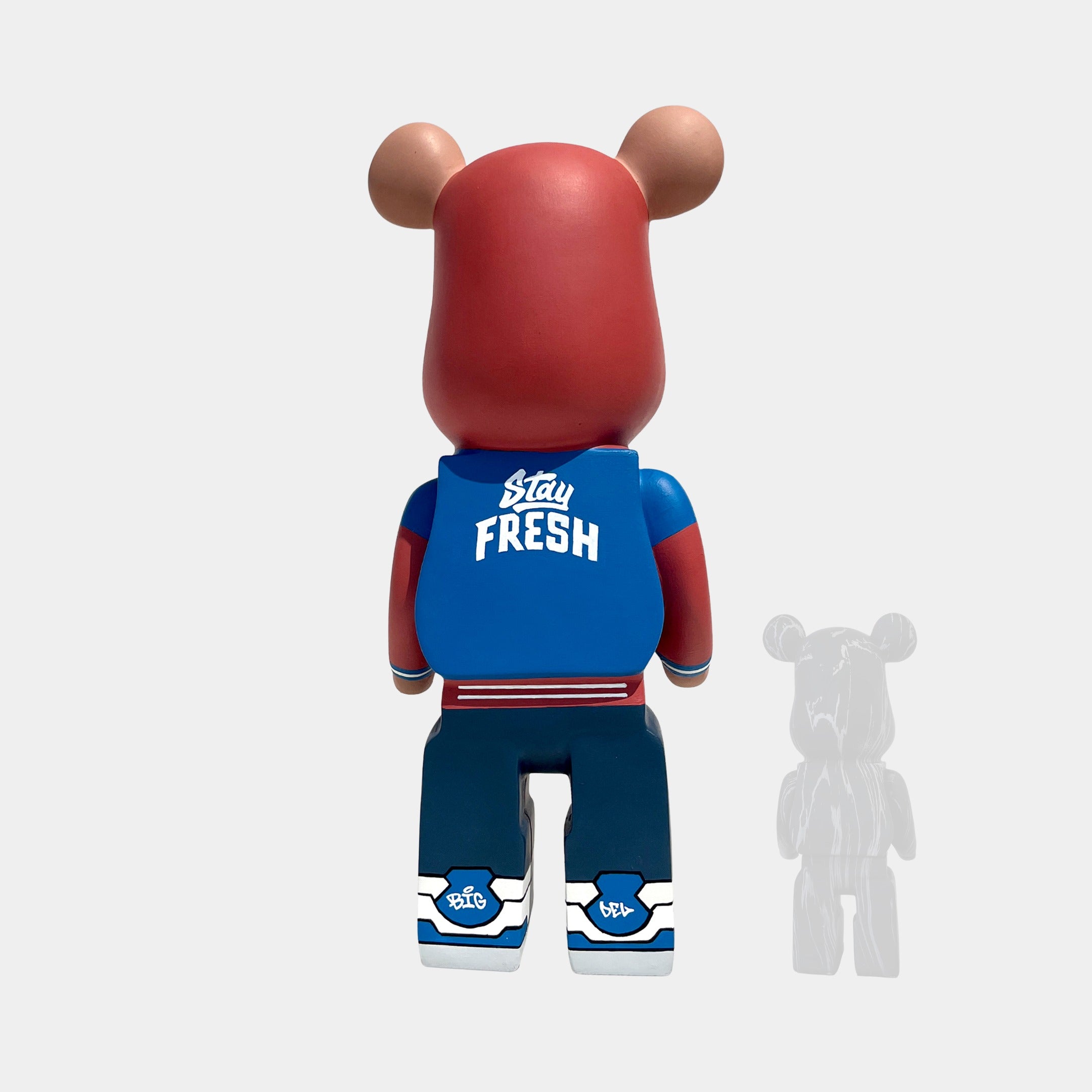 Seen from behind, the Fresh Grizz Bear Sculpture - 50cm by Giant Sculptures sports streetwear: red hoodie, blue “Stay Fresh” jacket, blue pants, and blue-white shoes. A right-side shadow completes this limited edition collectible.