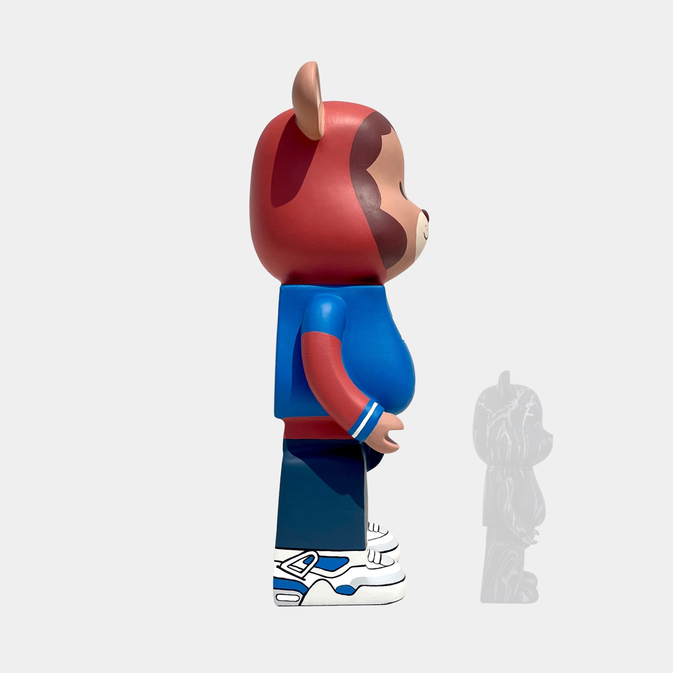 The Fresh Grizz Bear Sculpture - 50cm by Giant Sculptures features a bear in a red hoodie, blue shirt, and sneakers standing in profile right, paired with a small translucent shadow bear on a plain white background.
