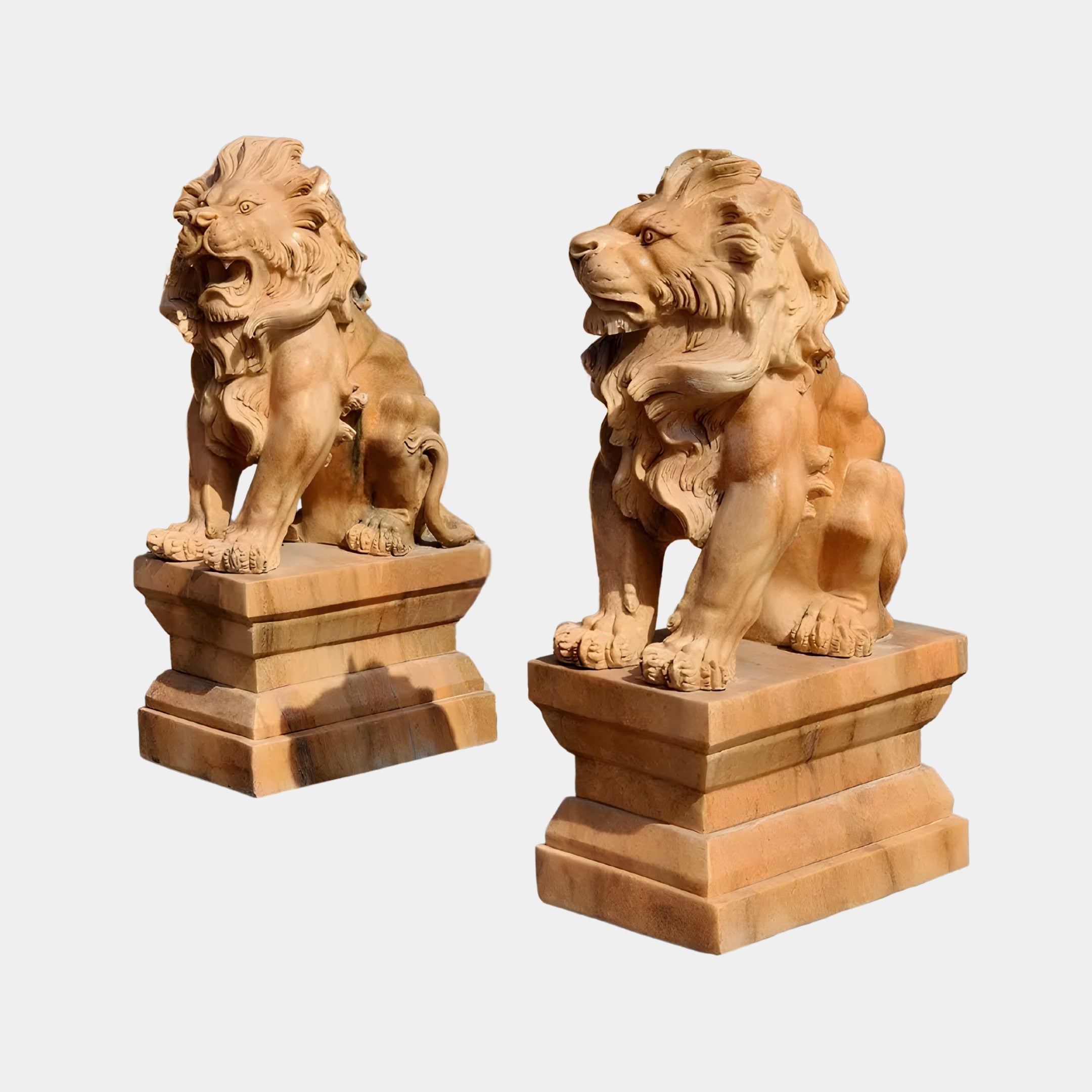 Two Giant Lion Yellow Marble Outdoor Sculptures by Giant Sculptures stand majestically on ornate pedestals. With intricate manes and fierce expressions, they face forward with layered bases enhancing their presence against a plain background. These statues are customizable to your liking.