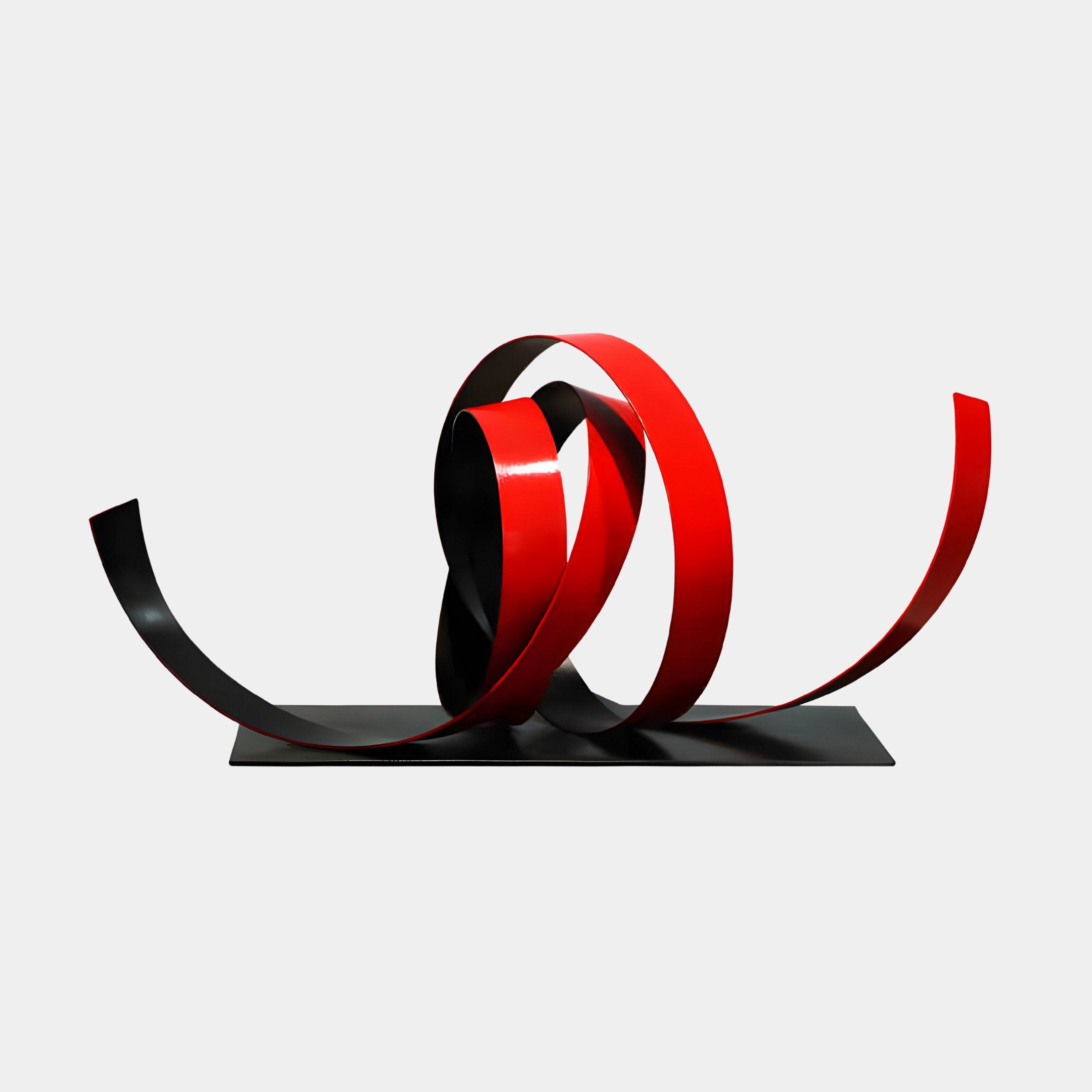 The Ribbon Red IV Abstract Steel Sculpture by Giant Sculptures, standing at 79cm, features intertwined red and black metallic ribbons that elegantly twist and loop. This modern piece, set on a flat black base, adds grace to contemporary spaces with its striking contrast against a plain white background.