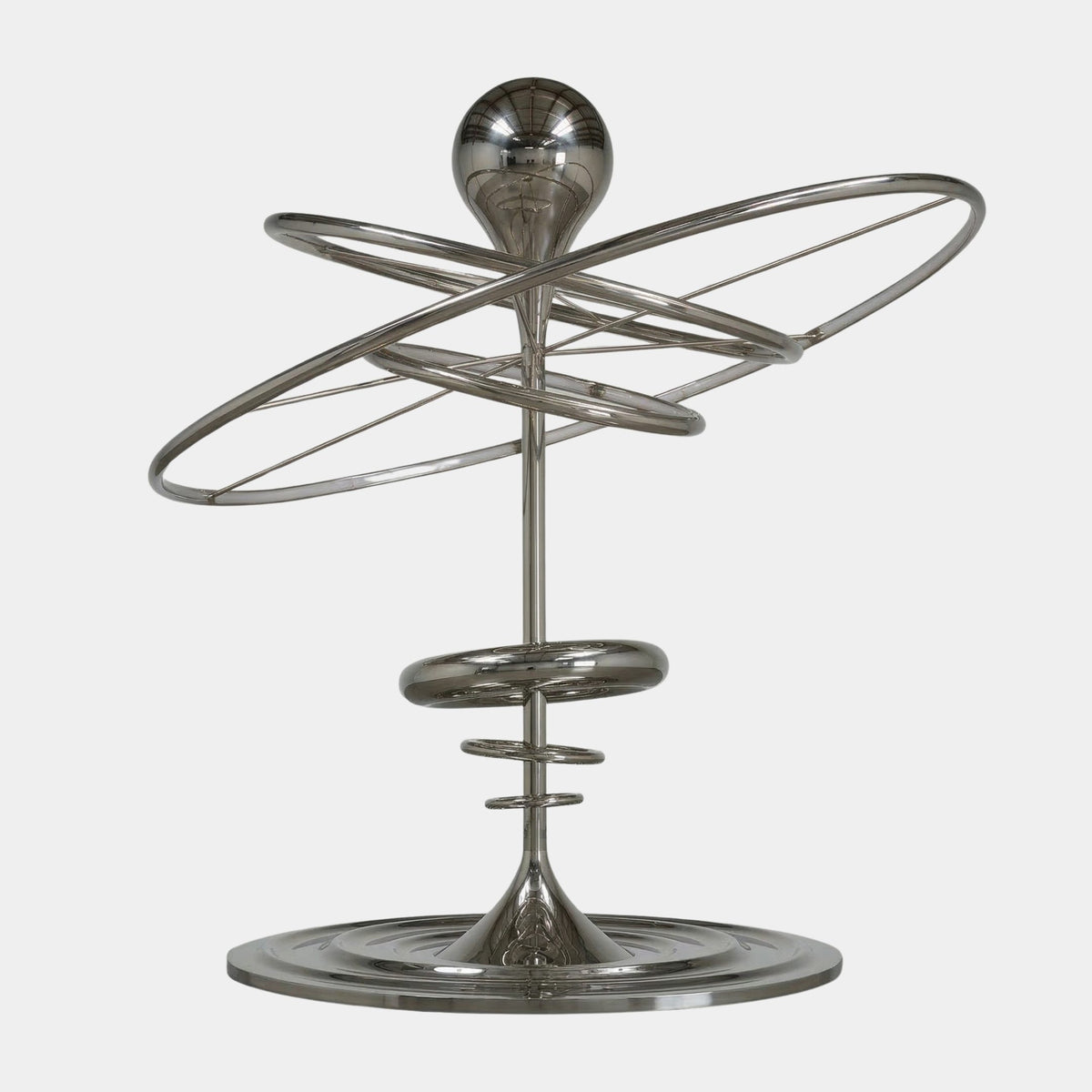 Silver Sphere with Orbital Rings Stainless Steel Sculpture (501cm) with a polished sphere atop a tapered column encircled by elliptical rings on a rippled round base, set against a plain white background.