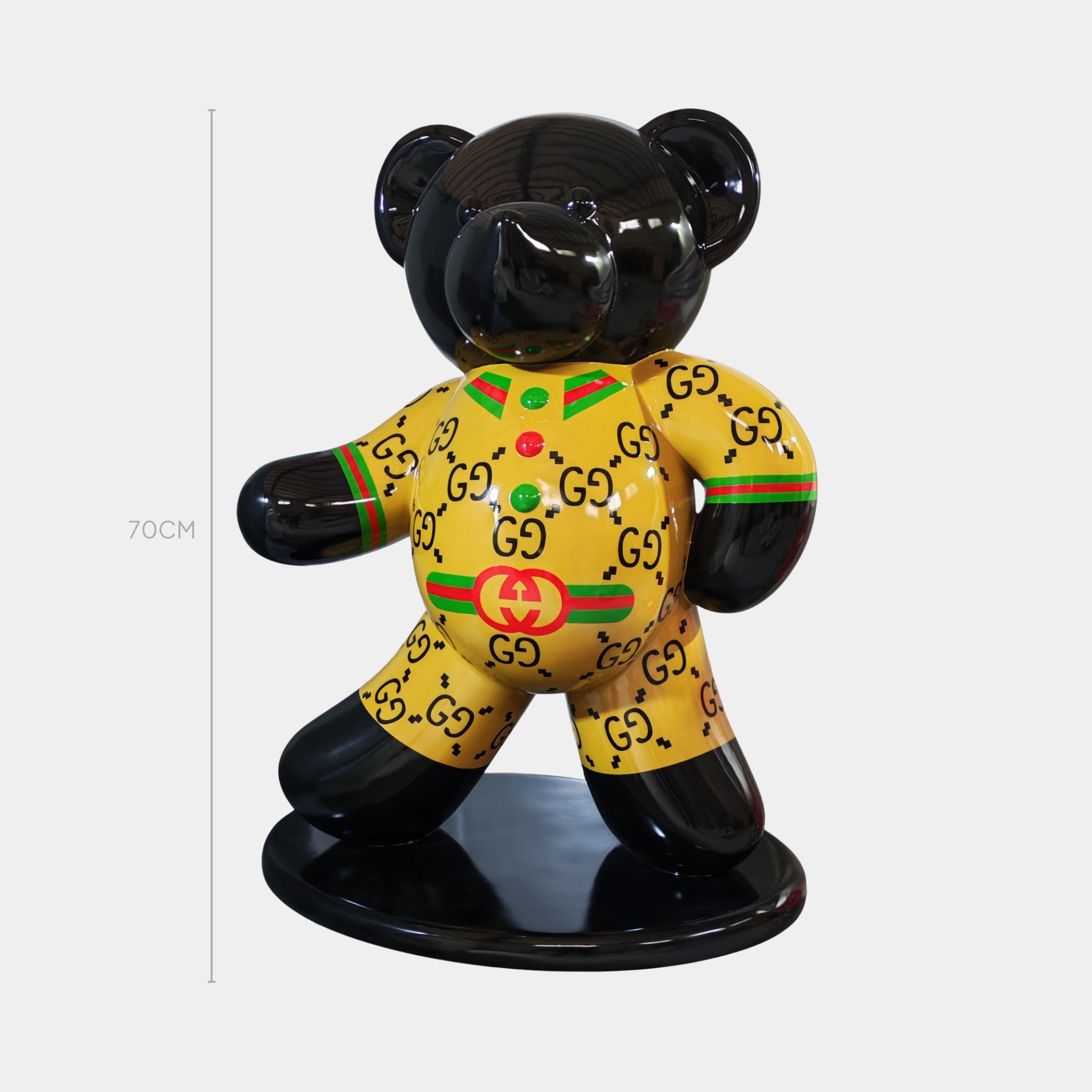 The Gacko Gucci Bear Sculpture by Giant Sculptures stands 70cm tall, featuring a glossy black finish, yellow “GG” pattern outfit, red and green stripes, logo accents, and comes on a round base—a pop art piece inspired by fashion.
