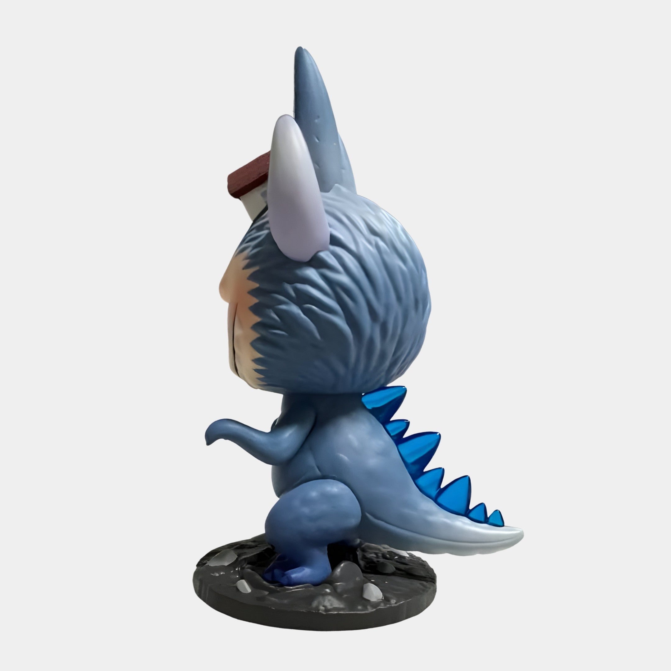 The Giant Sculptures Monsterverse Spiral Beast Labubu Sculpture (100cm) features a blue, dinosaur-like chibi with pointy ears, sharp spikes, and a stubby tail standing upright on a textured black base in a side view.