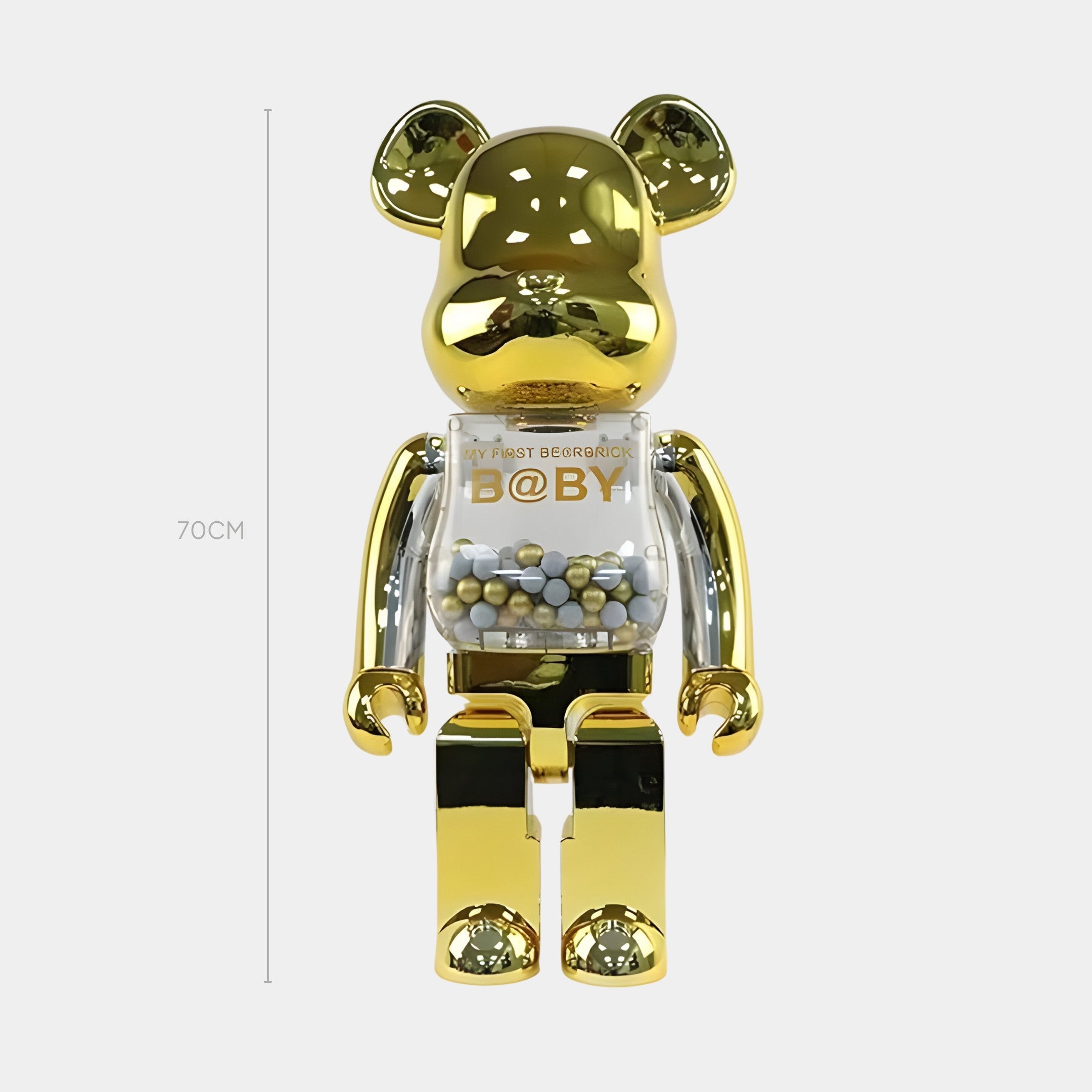 The Golden Chrome Beads Bear Sculpture - 70cm by Giant Sculptures stands upright with a shiny gold finish, transparent torso filled with golden chrome beads, and MY FIRST BE@RBRICK B@BY printed on its chest.