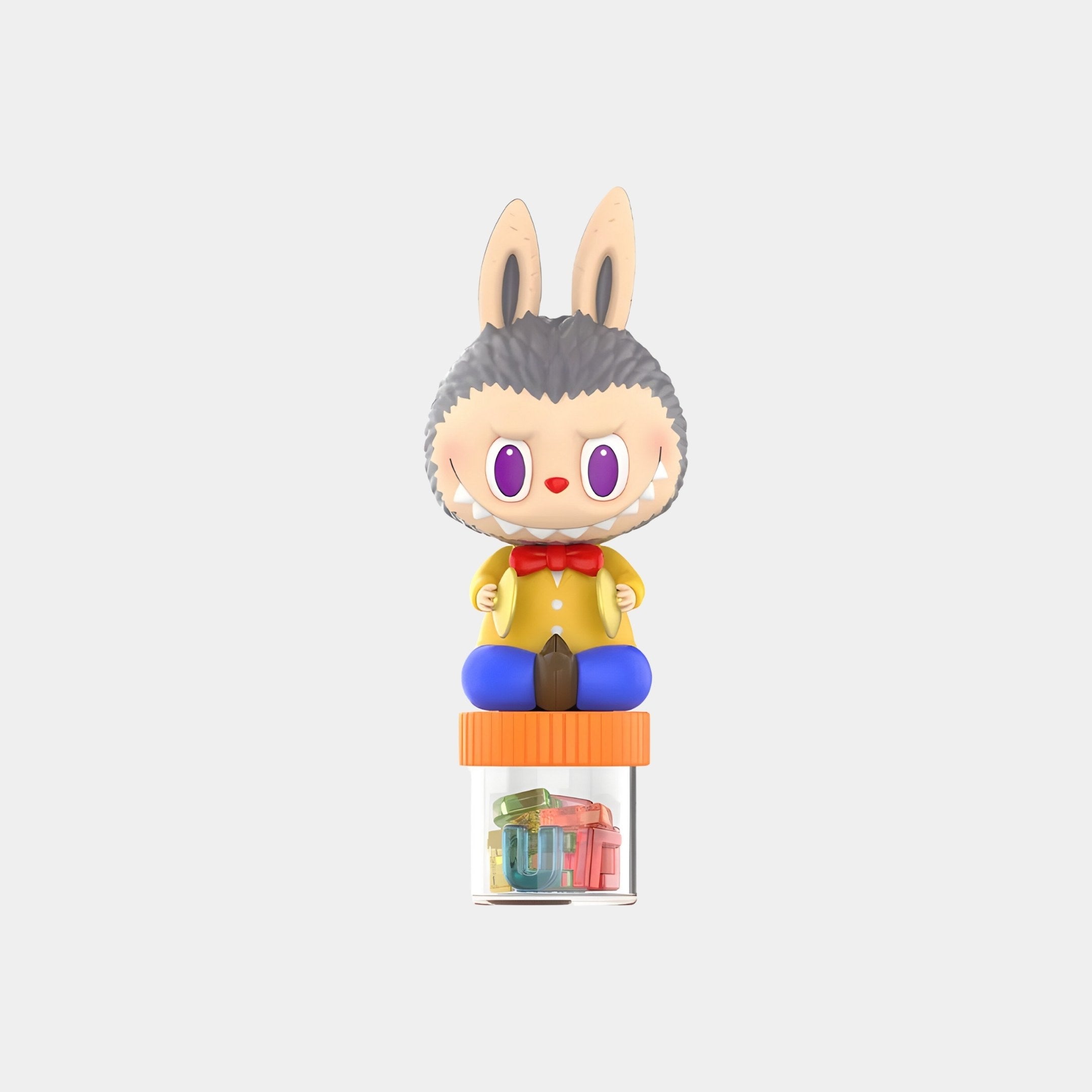 The Hard Candy Labubu Figure (7-10cm) by Giant Sculptures features a wolf-like head, big pink eyes, yellow jacket, red bow tie, and blue pants sitting on a transparent candy jar filled with colorful alphabet letters.