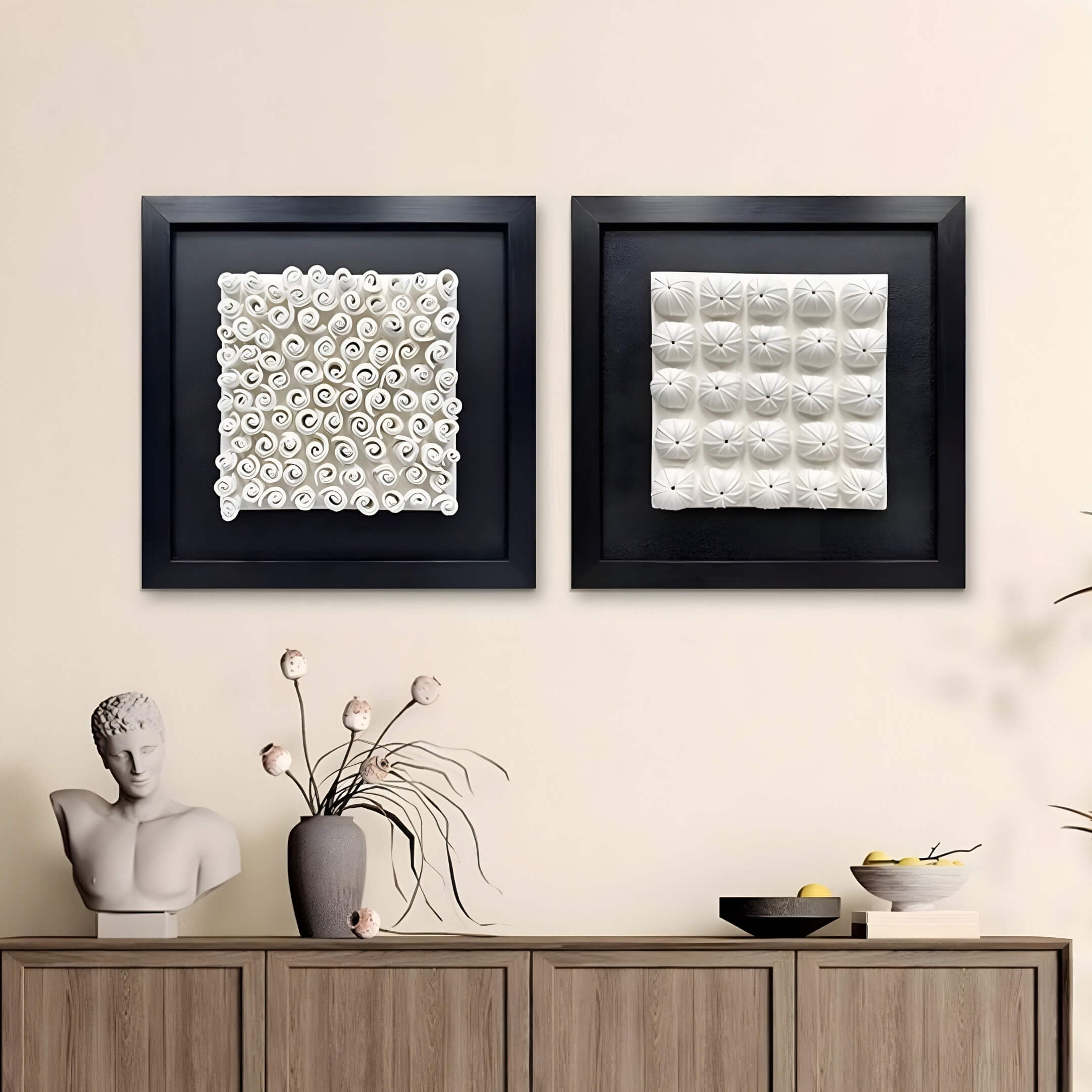 A minimalist room highlights modern interiors featuring two framed 3D wall sculptures: Harmonia 3D Ceramic Grid Wall Sculpture With Black Frame by Giant Sculptures and a swirling piece. Below, a wooden shelf displays a bust, vase with flowers, and black tray with a bowl and cup.