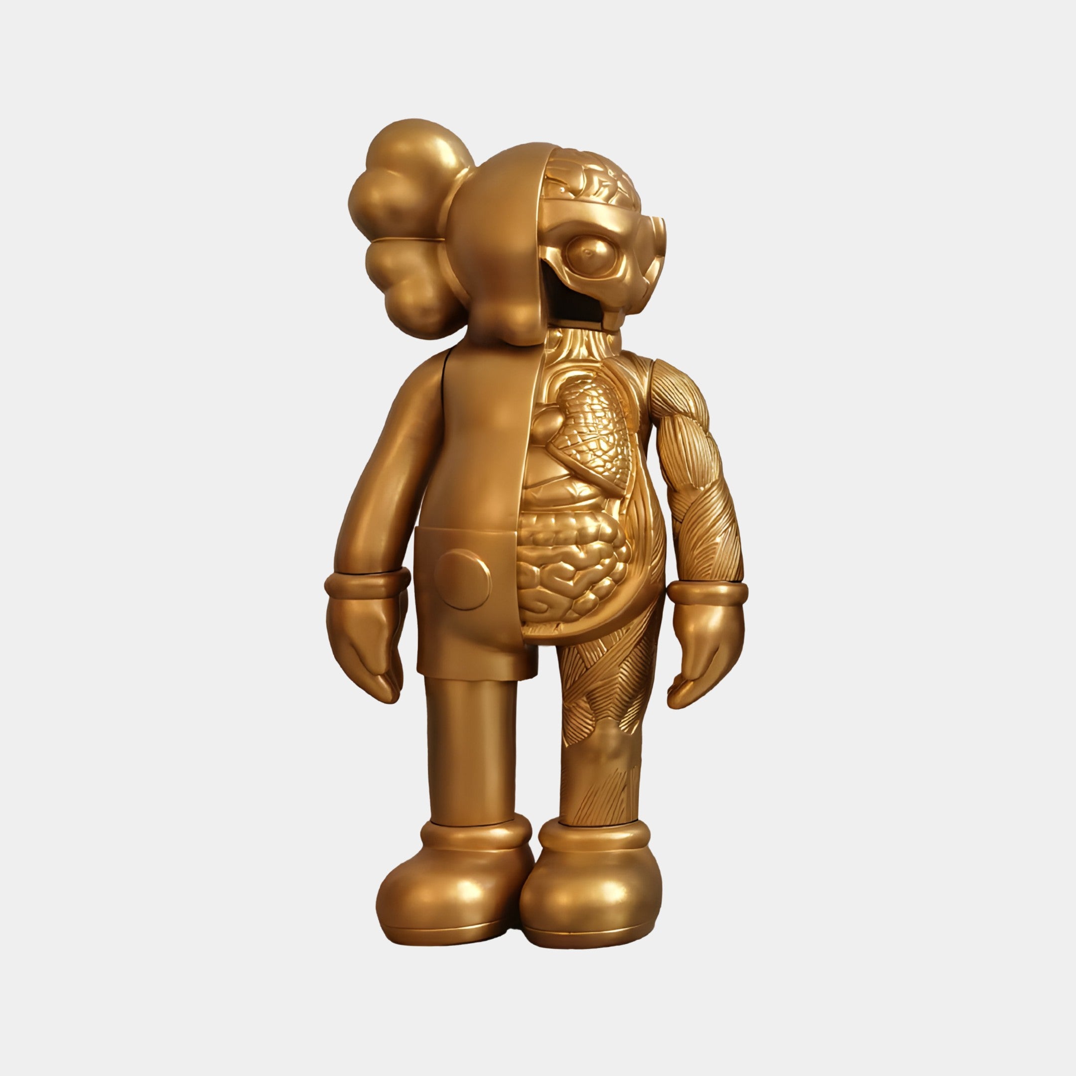 Giant Sculptures Champagne Satin Gold Iconify Anatomy Figure - 20cm is a striking sculpture split in half, one side with a satin-gold finish and the other revealing an intricate resin interior, featuring large shoes and distinctive rounded ears.