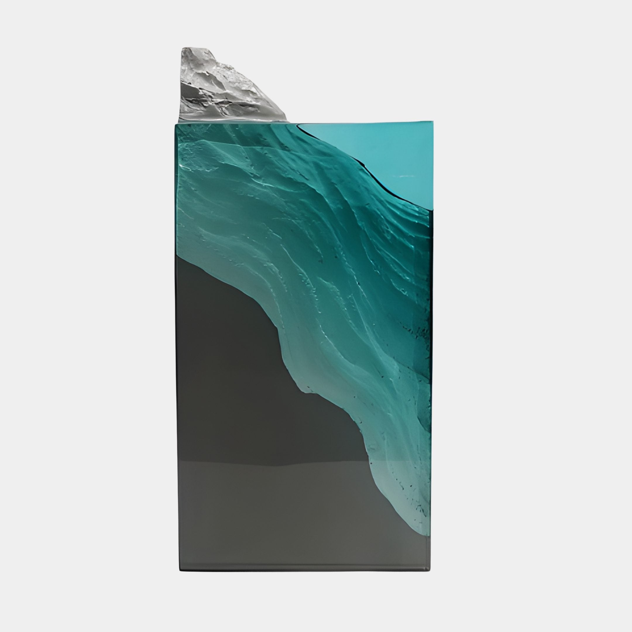 Giant Sculptures Teal Resin Ocean Wave Grey Crag Pedestal, 41cm, side view of a translucent teal wave curling over a grey base with a rocky peak, on white.