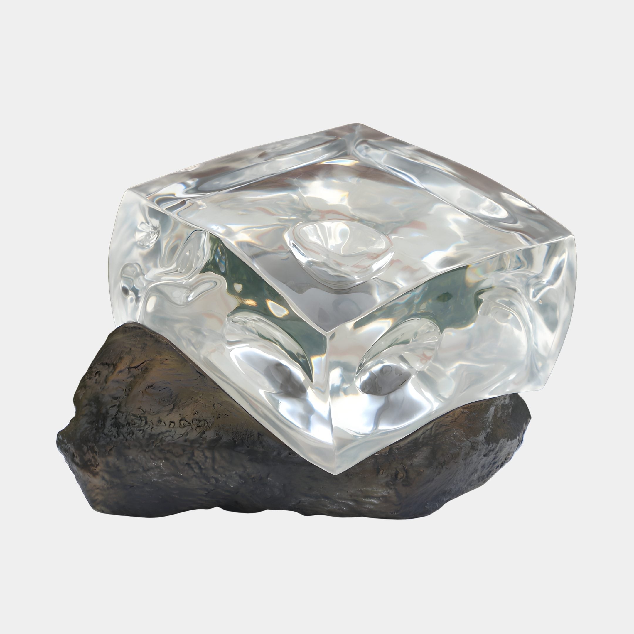 Giant Sculptures Clear Fluid Cube on Rock Base resin sculpture, 40cm, with a transparent fluid-edged cube resting on a bronze-grey rock against a plain background.