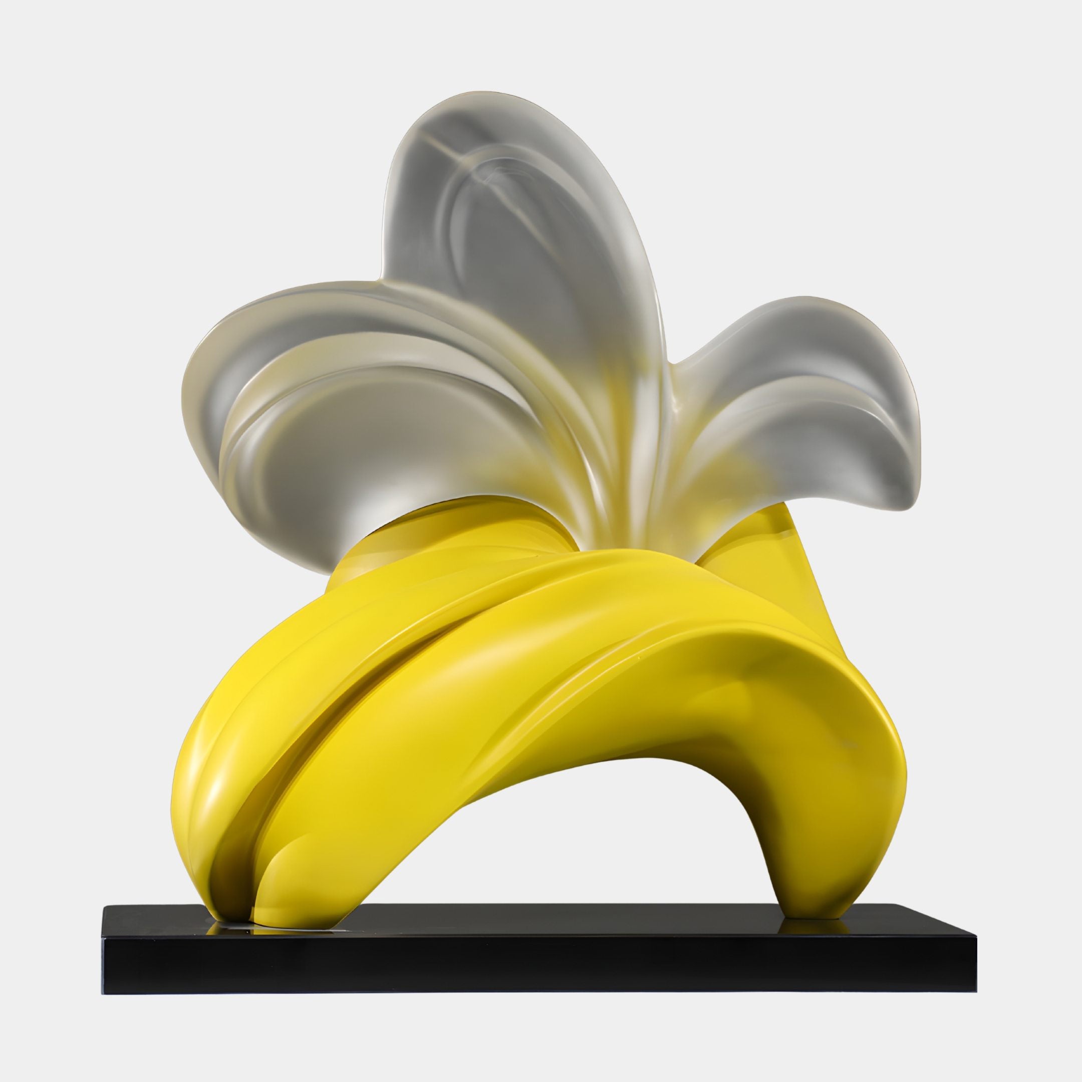 Giant Sculptures Yellow & Frosted Petal Bloom abstract banana-inspired resin sculpture with glossy yellow peel and silver-grey interior on a black base.