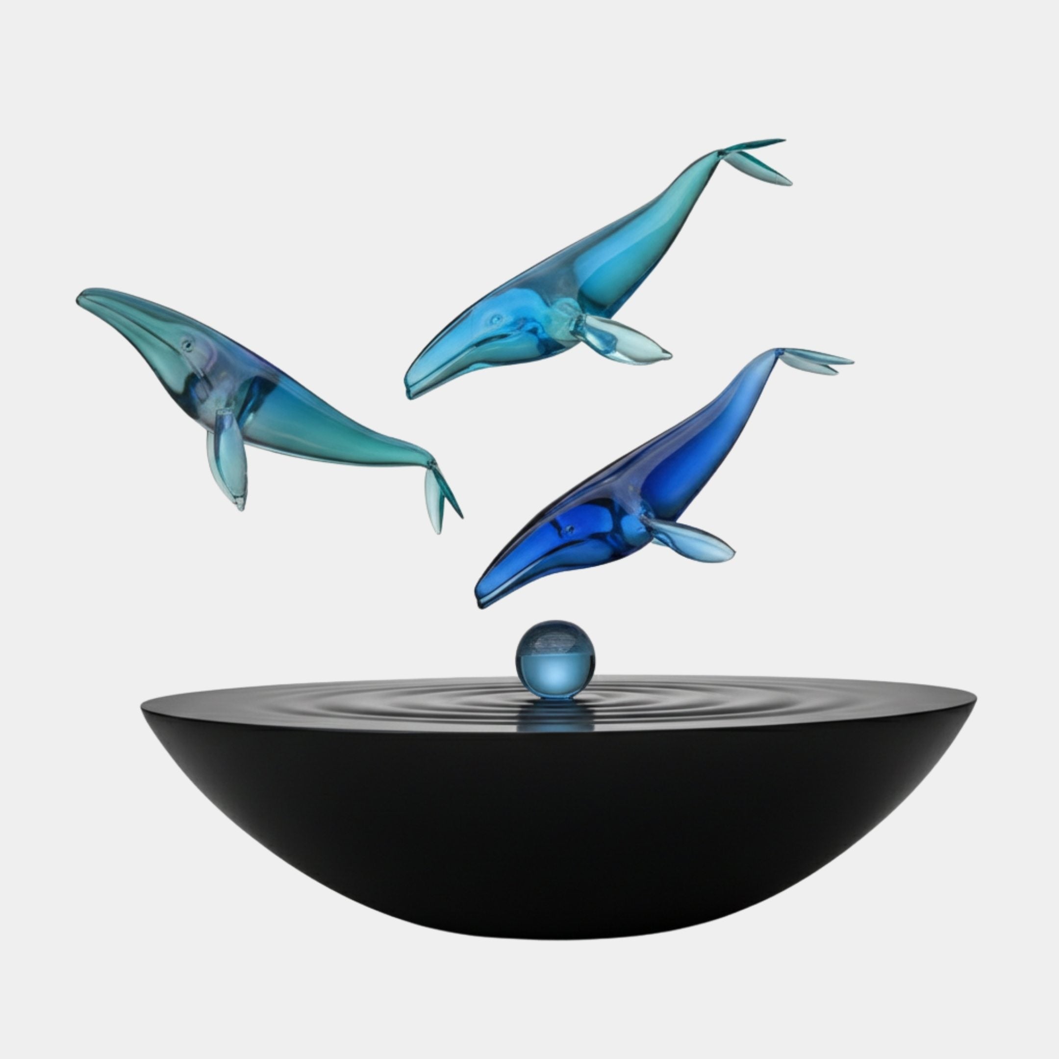 Giant Sculptures Blue Humpback Whale Trio resin sculpture with three translucent blue whales leaping above a glossy black basin and sphere on a white background.
