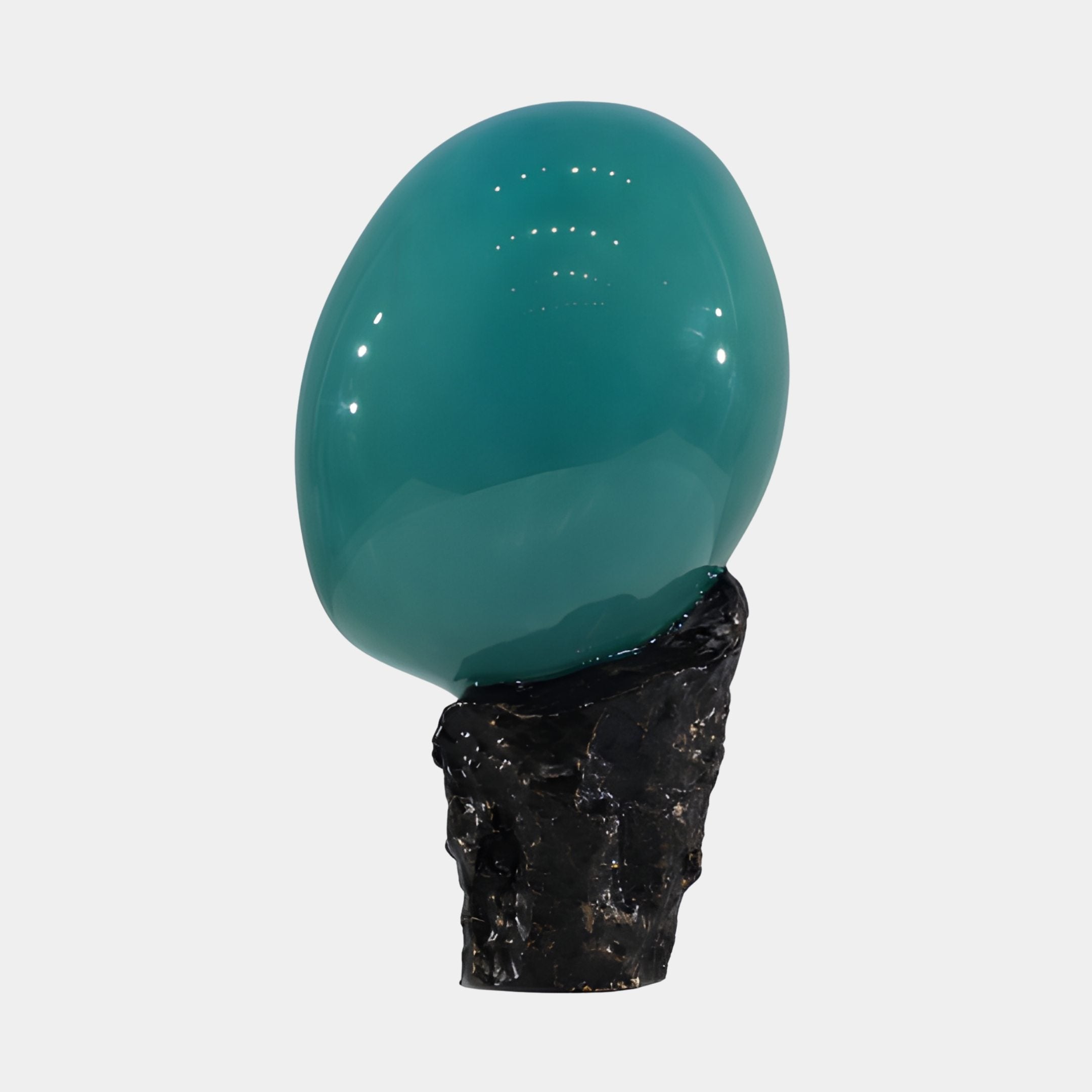 Glossy teal resin sphere balanced on a rugged black rock base, shown against a plain light background as part of the Giant Sculptures 40cm piece.