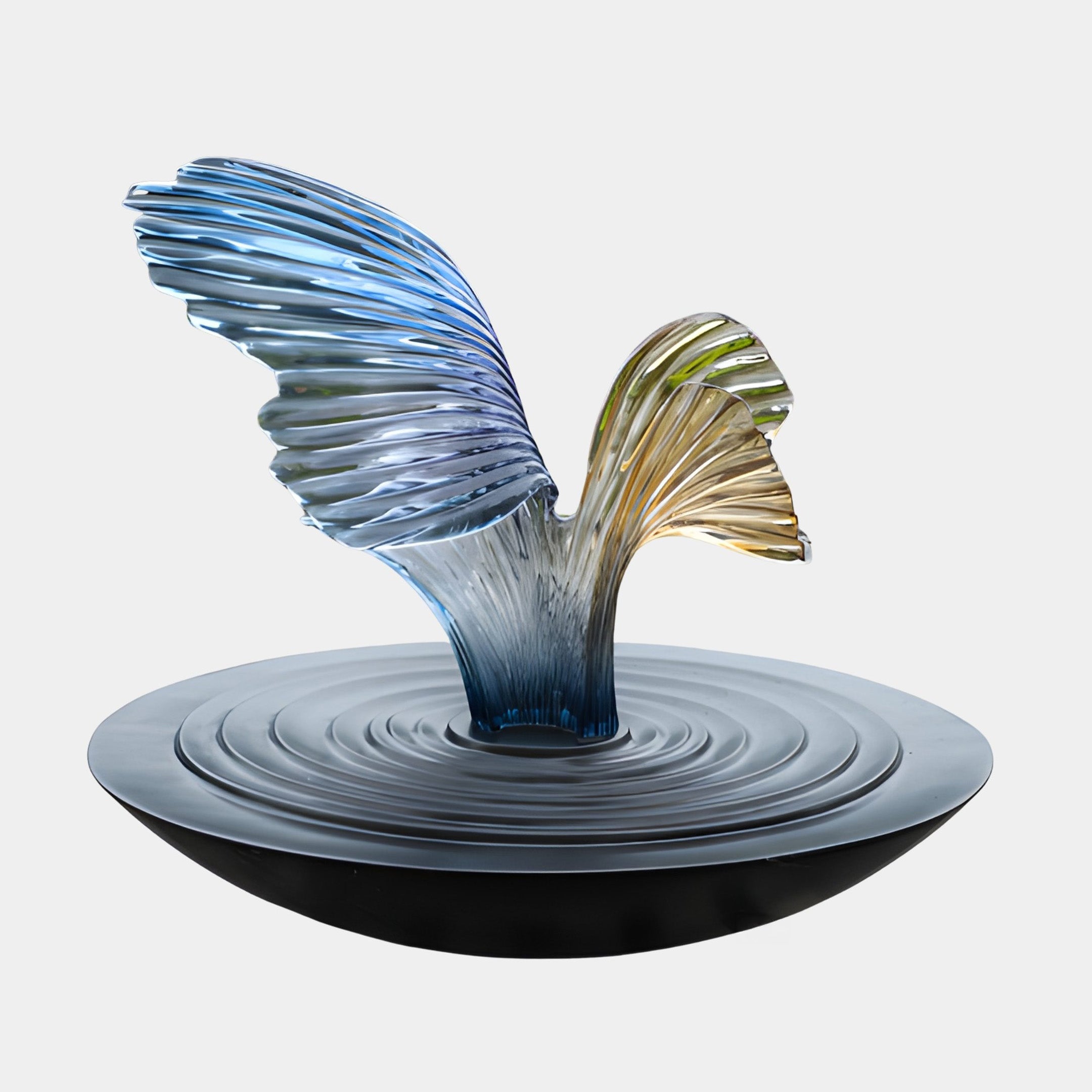 Blue and gold iridescent fluid wing resin sculpture by Giant Sculptures, rising from a black rippled disc base against a plain light background.
