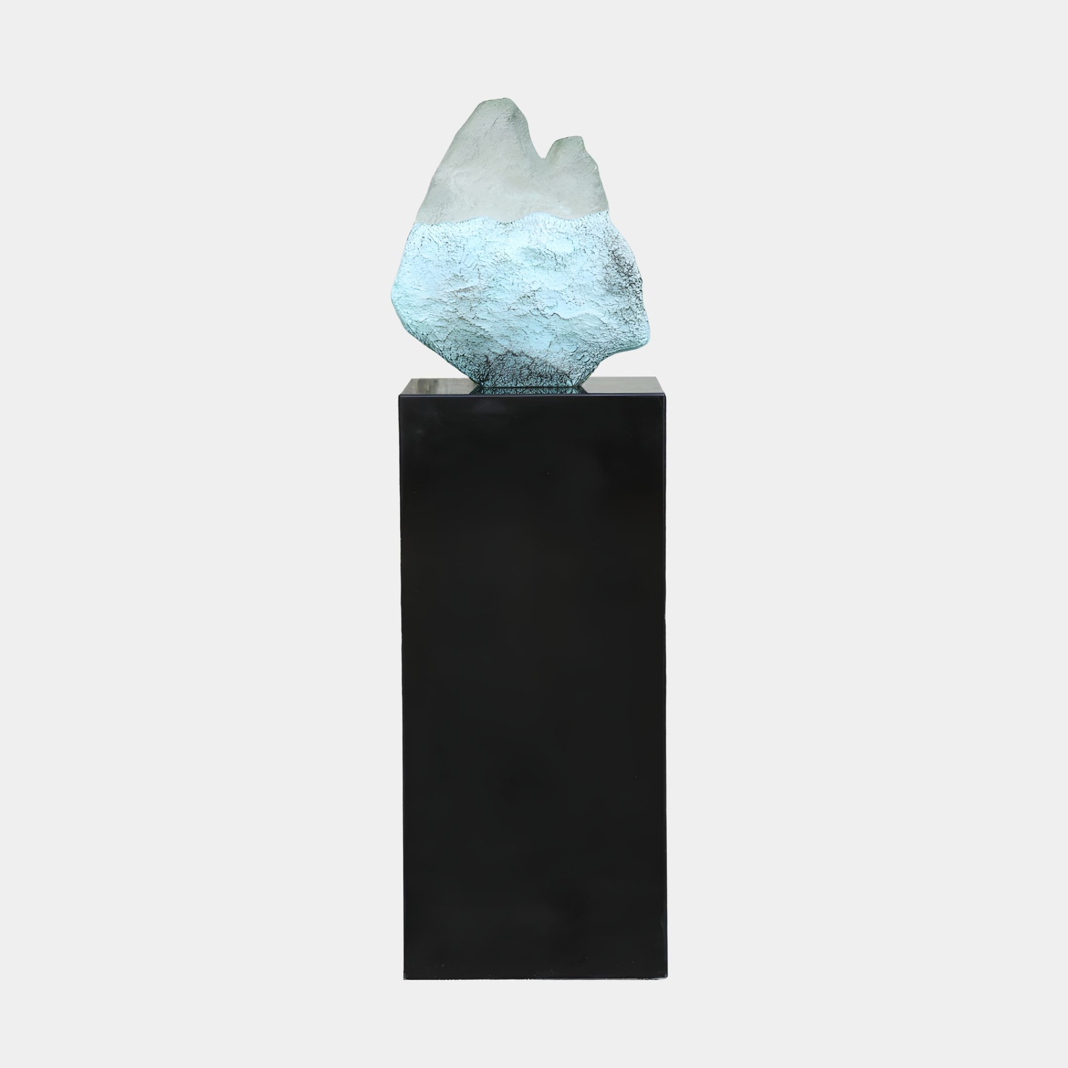 Frosted Crystal Peak Resin Sculpture by Giant Sculptures, an icy white and pale blue peak-shaped form displayed on a tall black pedestal against a plain background.