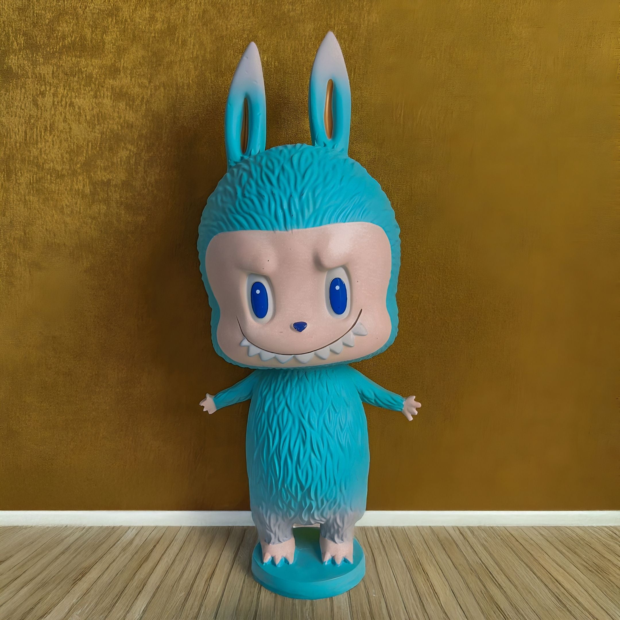 The Little Monster Blue Labubu Sculpture - 100cm by Giant Sculptures features a blue, furry figure with upright ears, big blue eyes, a mischievous grin, and tiny arms—adding playful charm to any space. Crafted from fibreglass.