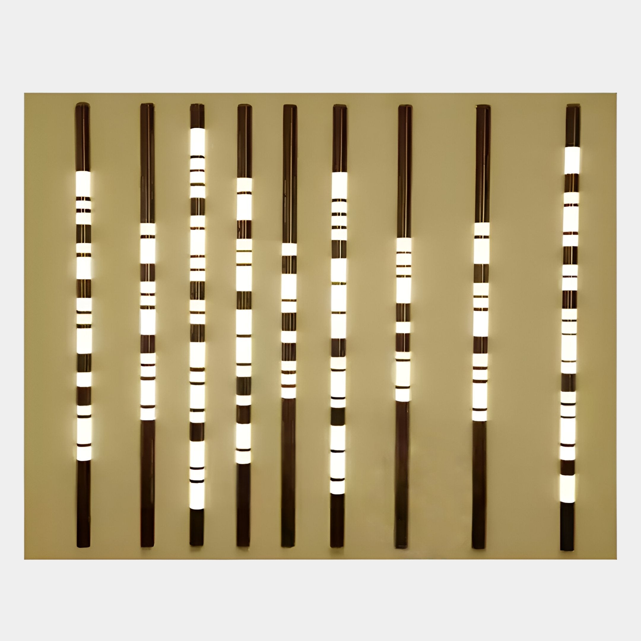 Nine Strata Gold LED Wall Art fixtures by Giant Sculptures, with alternating dark and illuminated bands, are evenly spaced on a beige wall—creating a sophisticated glowing pattern ideal for luxury interiors.