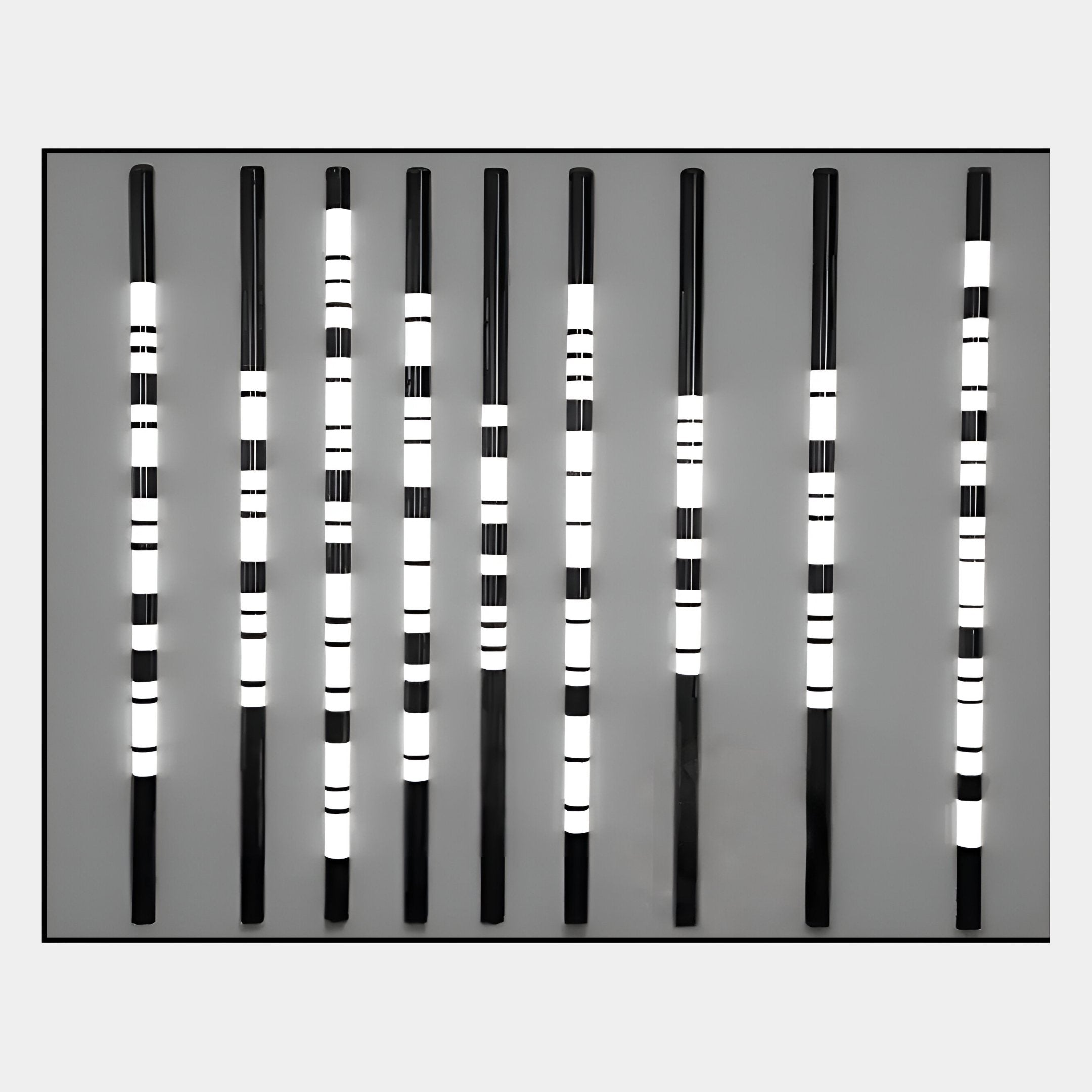 The Strata Silver LED Wall Art by Giant Sculptures features nine vertical black rods with varying white stripes on a gray background, creating a minimalist barcode effect that highlights modern, industrial-chic design.