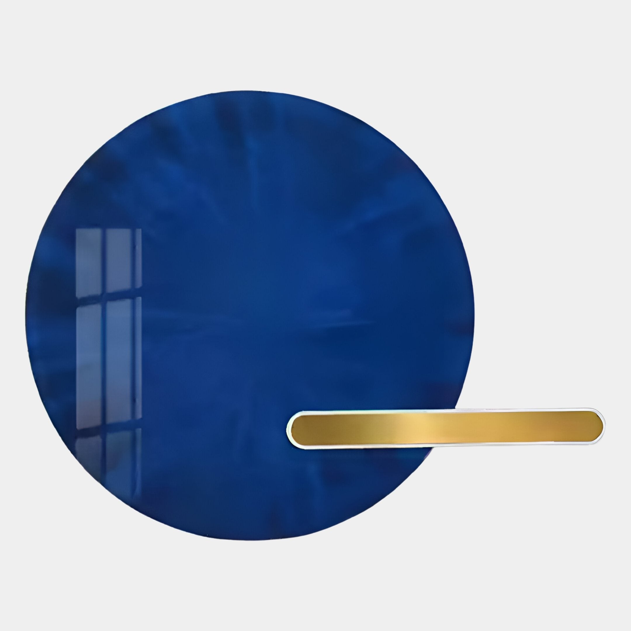 The Lumea Sapphire 3D LED Crystal Porcelain Wall Art by Giant Sculptures features a large circular sapphire blue reflective surface with a window’s reflection and a horizontal gold bar on the lower right, set against a white background.