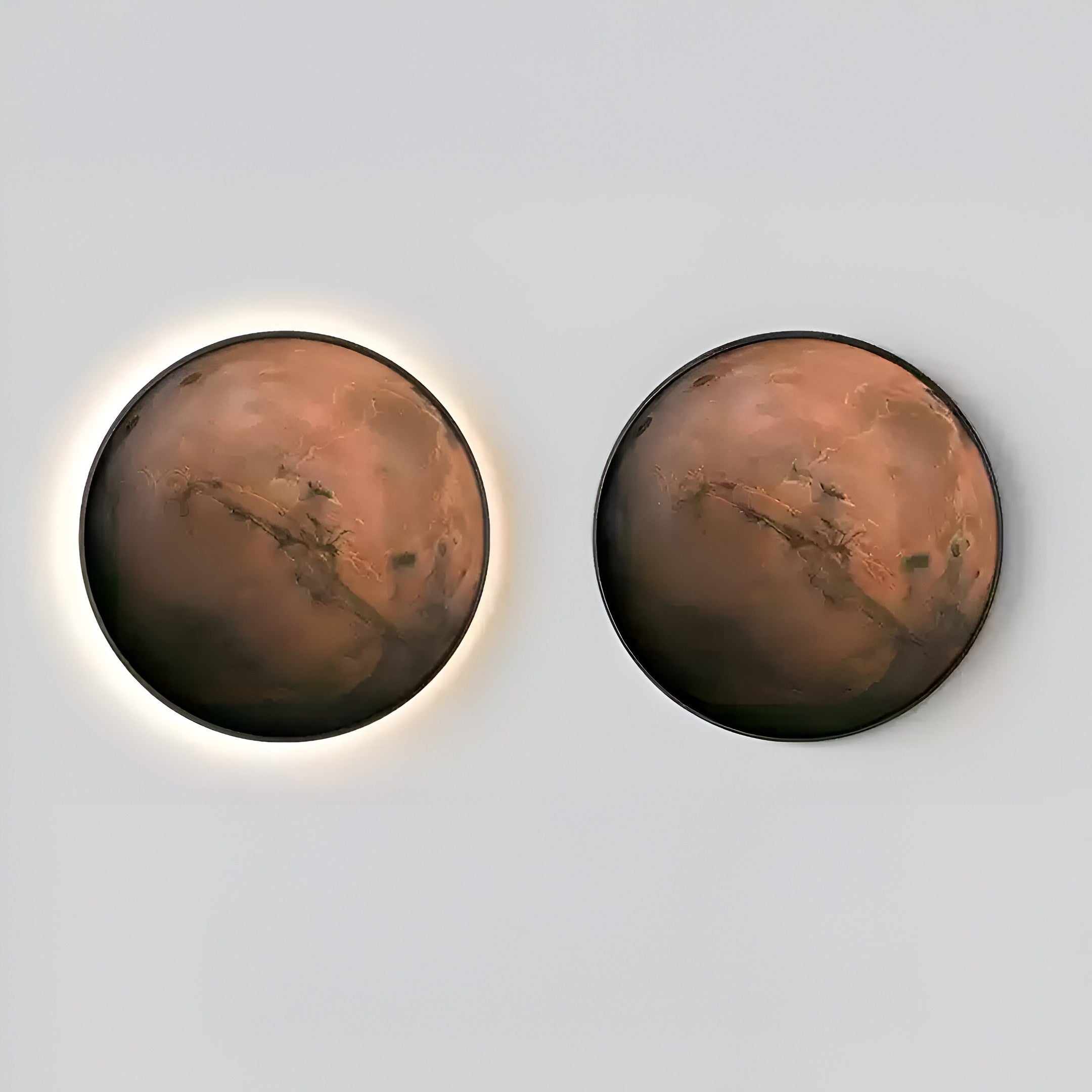 The Galaxia Mars Crystal Porcelain LED Wall Art by Giant Sculptures features two circular pieces mimicking Marss surface; the left softly aglow, while the right is unlit. Both exhibit a reddish-brown texture akin to Martian soil.