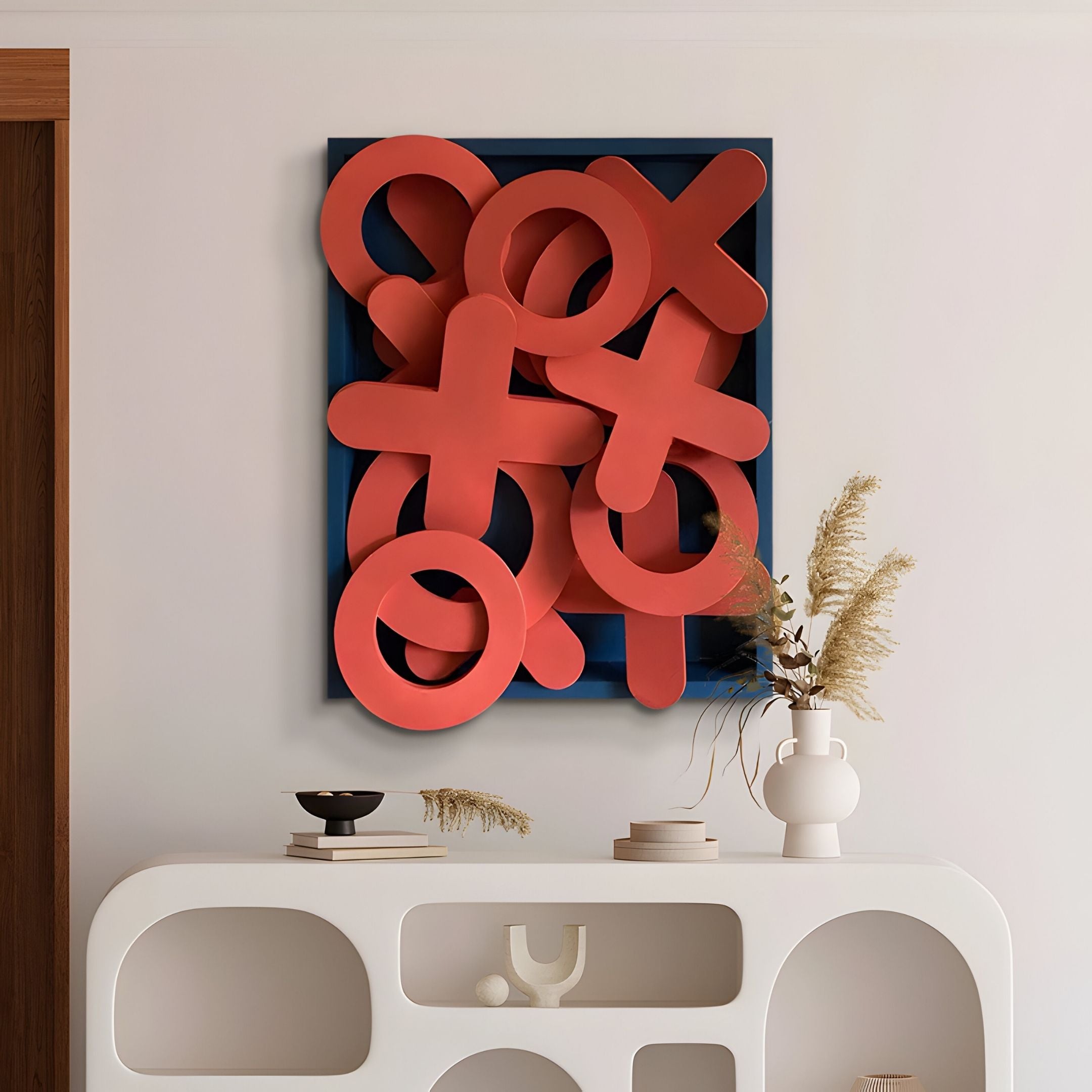 A modern interior displays a white console table with decorative vases, accented by the Giant Sculptures Typova Red X&O Wood Carving 3D Wall Art—a bold Nordic piece featuring red X and O shapes on a blue background.