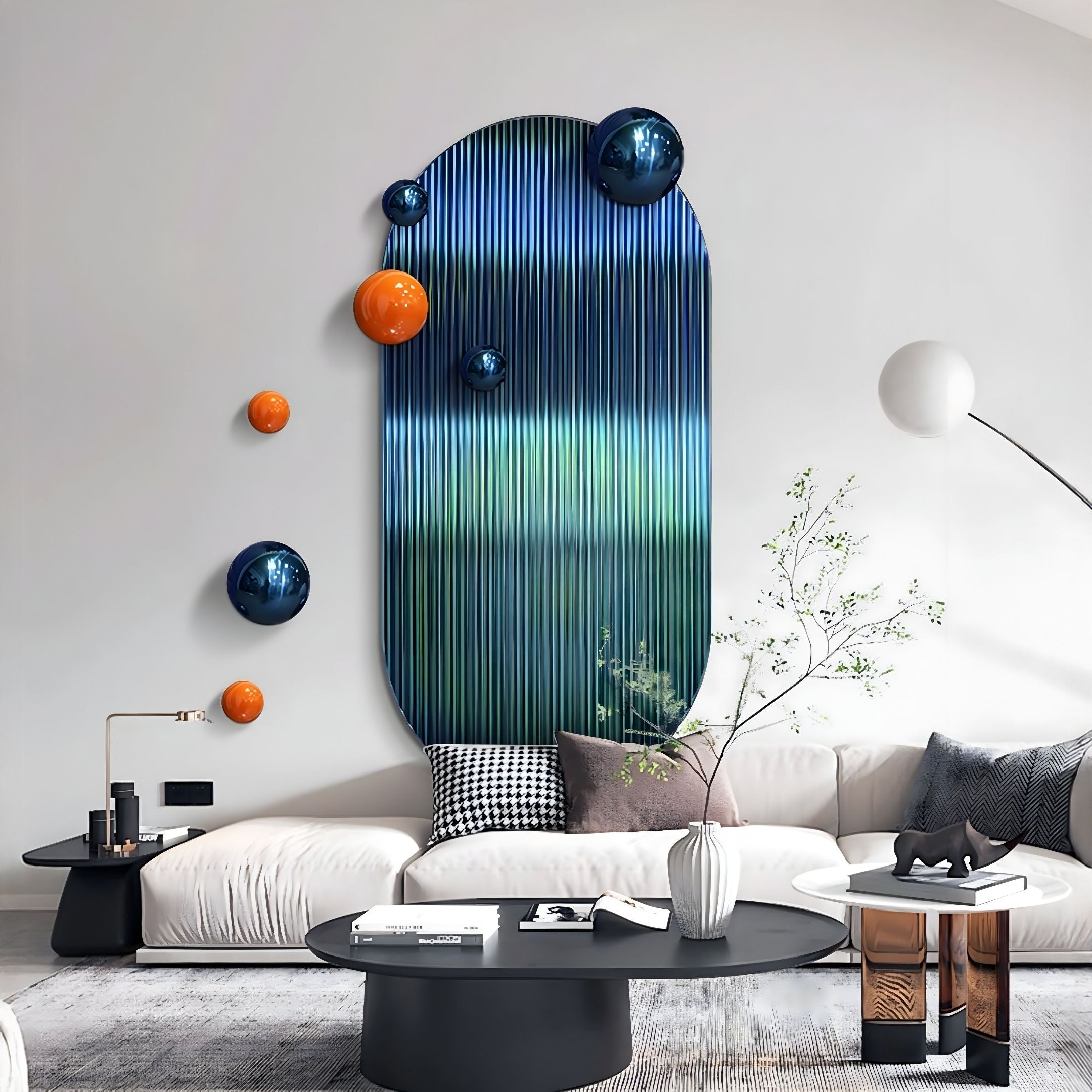 A modern living room features a white sofa, black tables, and minimal decor. The focal point is the Virellon Blue Gradient 3D Wall Art with navy & orange metal balls by Giant Sculptures, accented by a floor lamp and vase with branches.