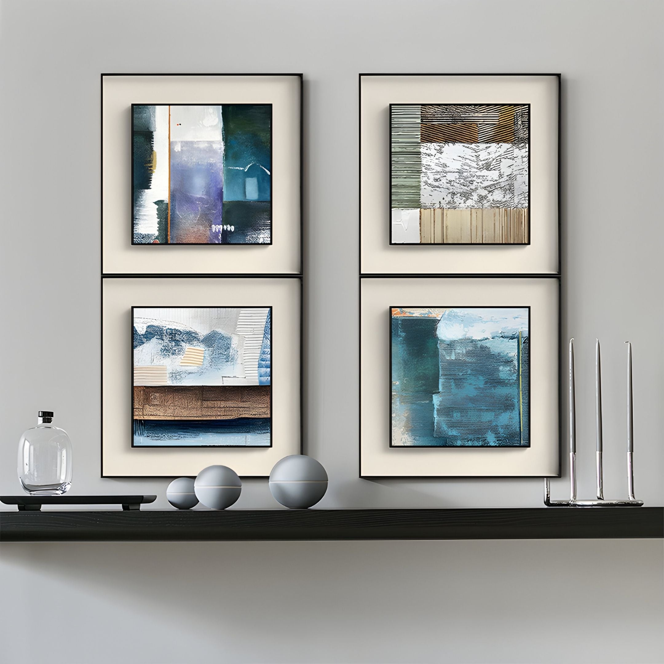 A minimalist shelf displays three round objects, a glass decanter, and four Giant Sculptures Aerolith Midnight Blend Abstract Textured Framed Wall Art pieces in blue, gray, and neutrals on a light gray wall.