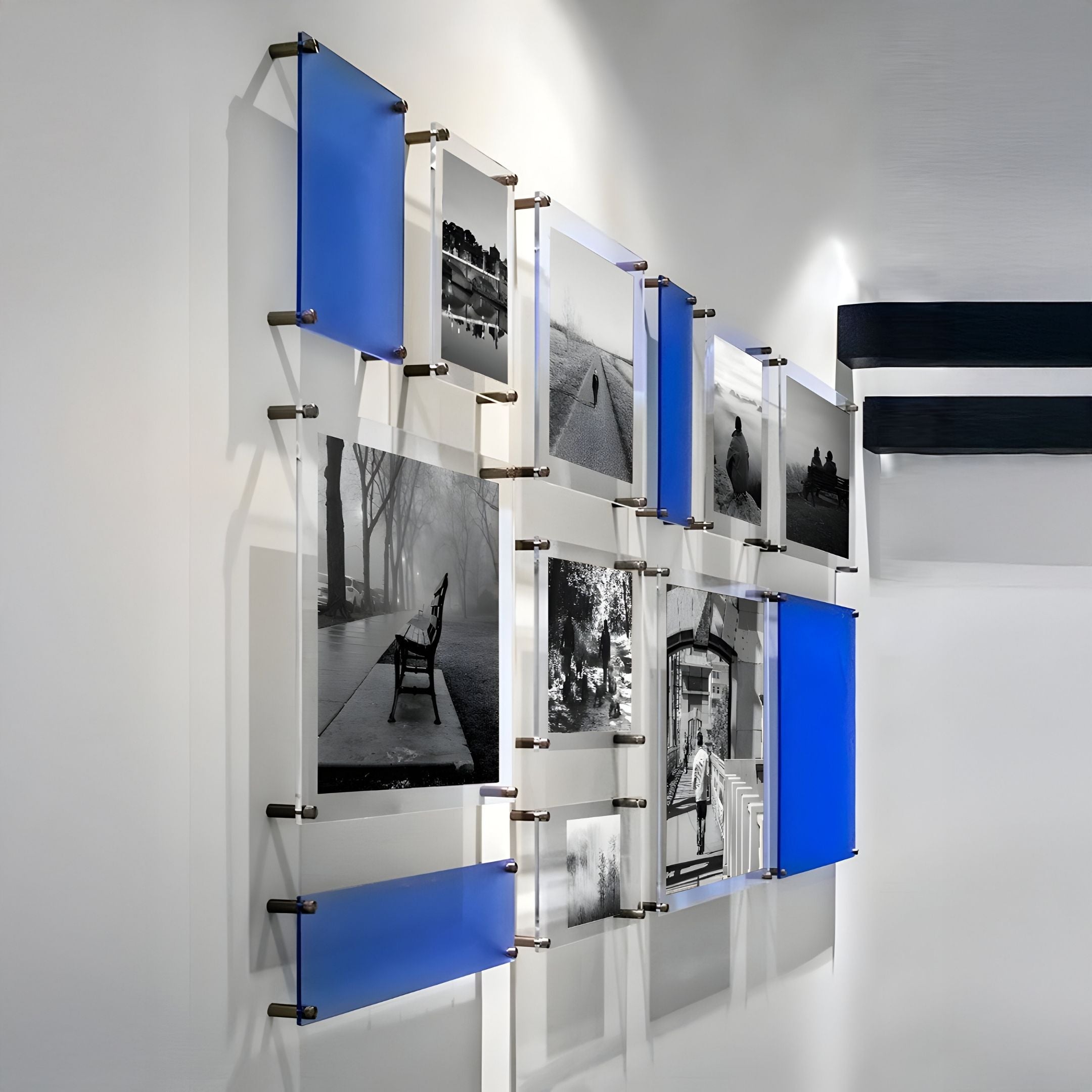 The Framegrid Blue Mixed-Size Gallery 12-Set Acrylic Wall Art by Giant Sculptures features black and white photos with blue translucent panels, mounted with metal brackets on a white wall for a modern, geometric look.