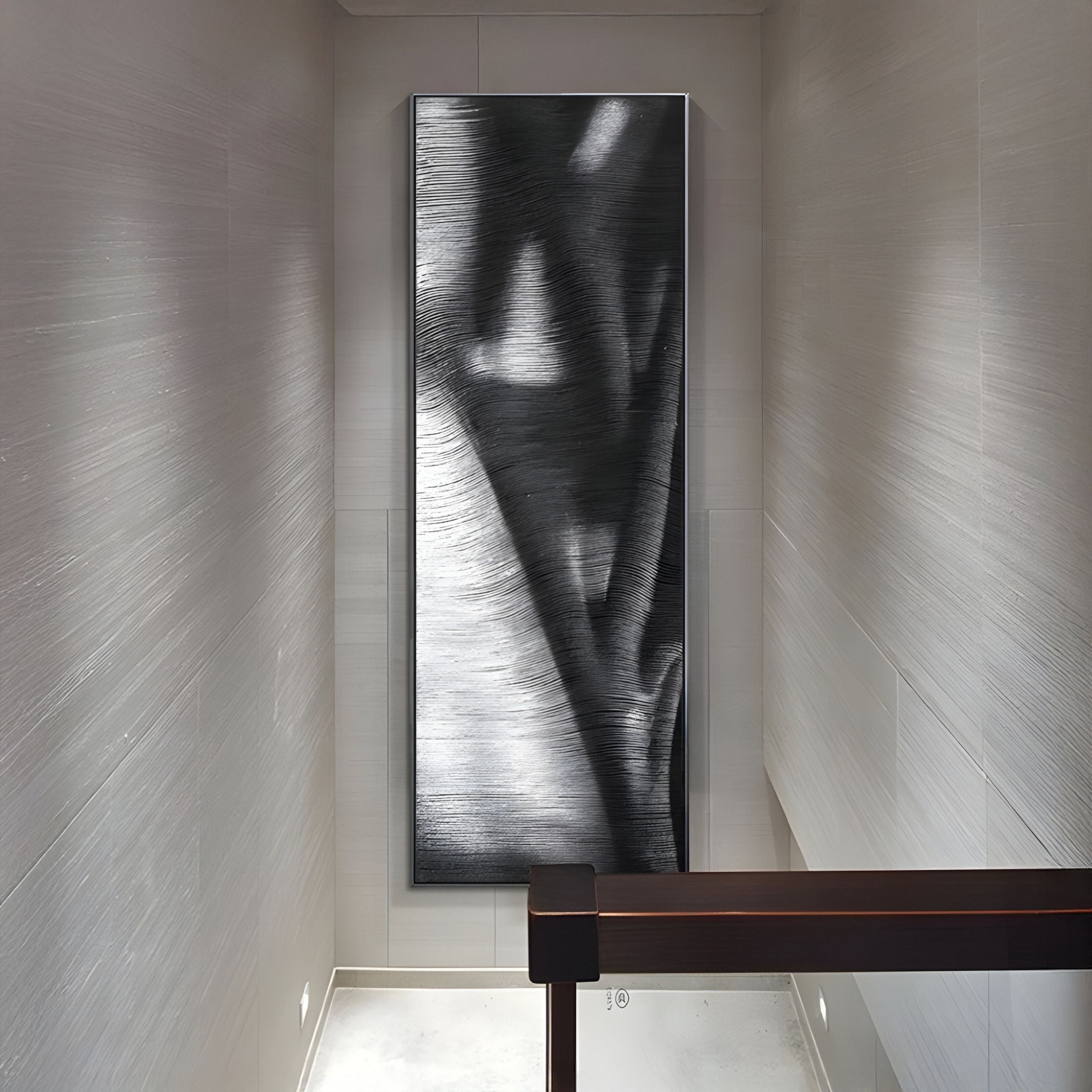 A modern hallway with light gray textured walls features the Rivara Obsidian Wave Vertical Hand-Painted Rope 3D Wall Art by Giant Sculptures at the end, its abstract organic shapes complementing a dark handrail for a striking minimalist look.