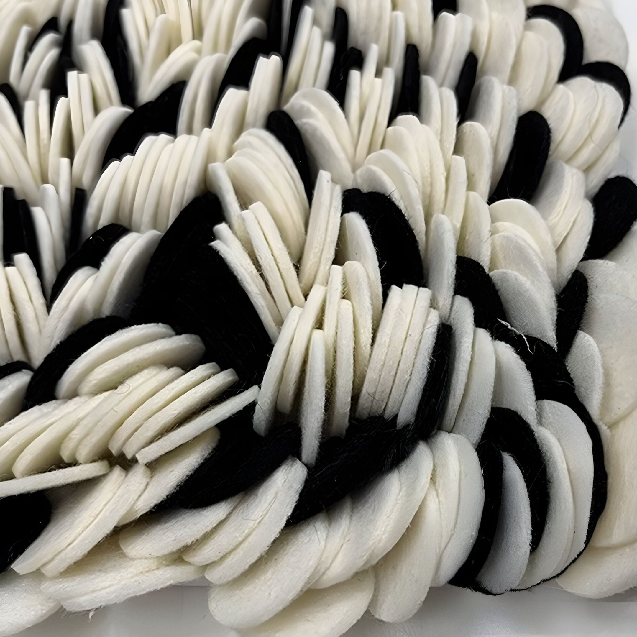 Petalus Black & Cream Layered Felt 3D Wall Art by Giant Sculptures features overlapping black and cream discs in a textured, wave-like pattern, creating a striking modern decor piece with alternating light and dark sections.