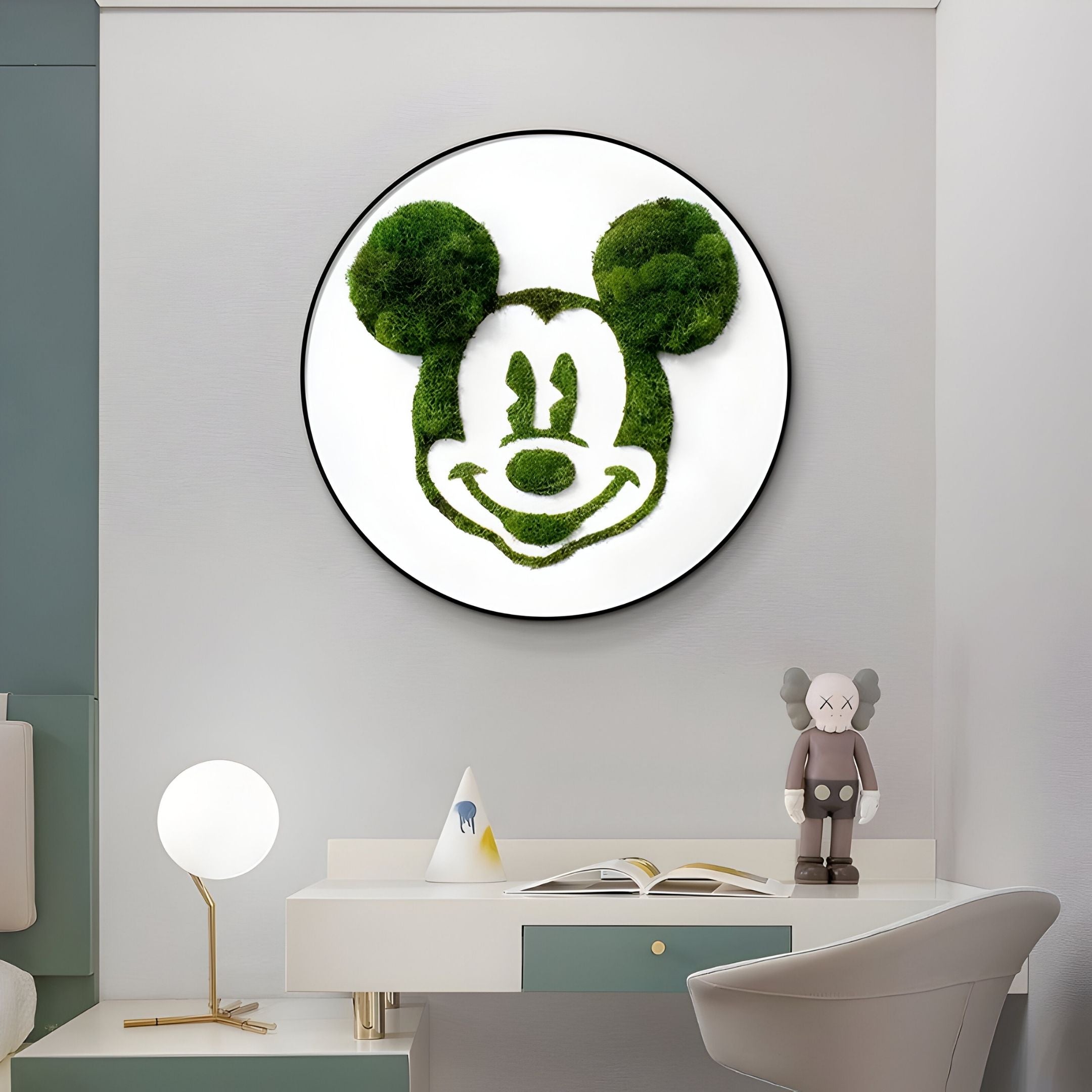 A modern room with desk, lamp, and figure features the Verdifable Round Green Mouse Silhouette Moss 3D Wall Art by Giant Sculptures—a striking Nordic decor piece with a green mouse on a white circular background above the desk.