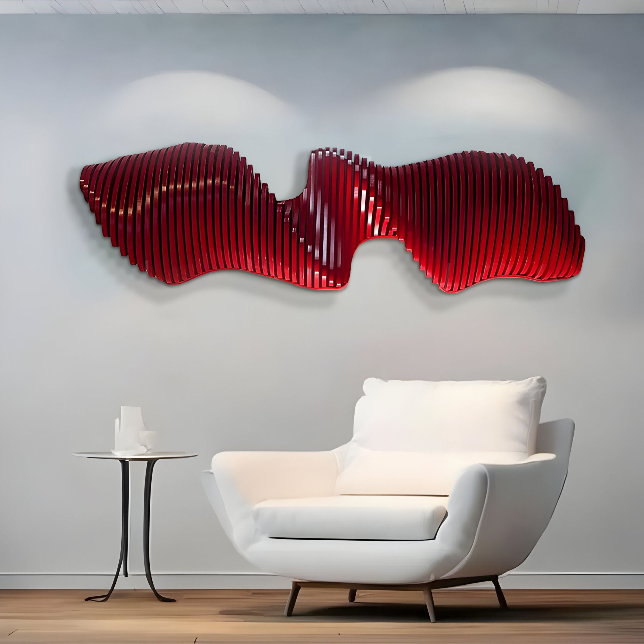 A modern living room with a white armchair and round side table features the Aeravox Red Waveform Sculptural 3D Wall Art by Giant Sculptures, its vibrant red curves adding a striking touch of modern decor to the light gray wall.