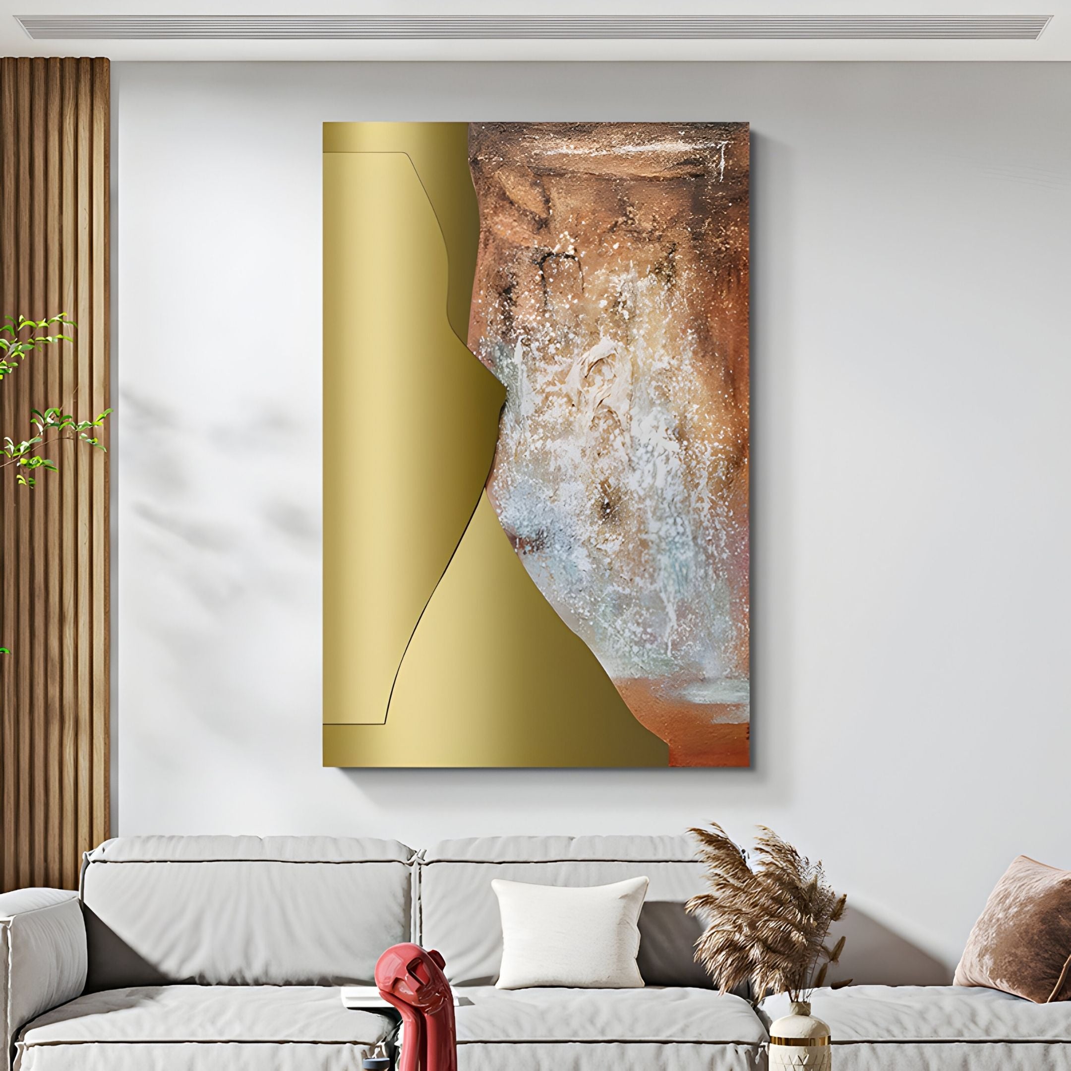The Aurivara Gold Metal & Earth Textured Abstract 3D Wall Art by Giant Sculptures hangs above a light gray sofa. A vase with dried plants and a red book rest on the coffee table, with sunlight streaming through wooden slats on the left.
