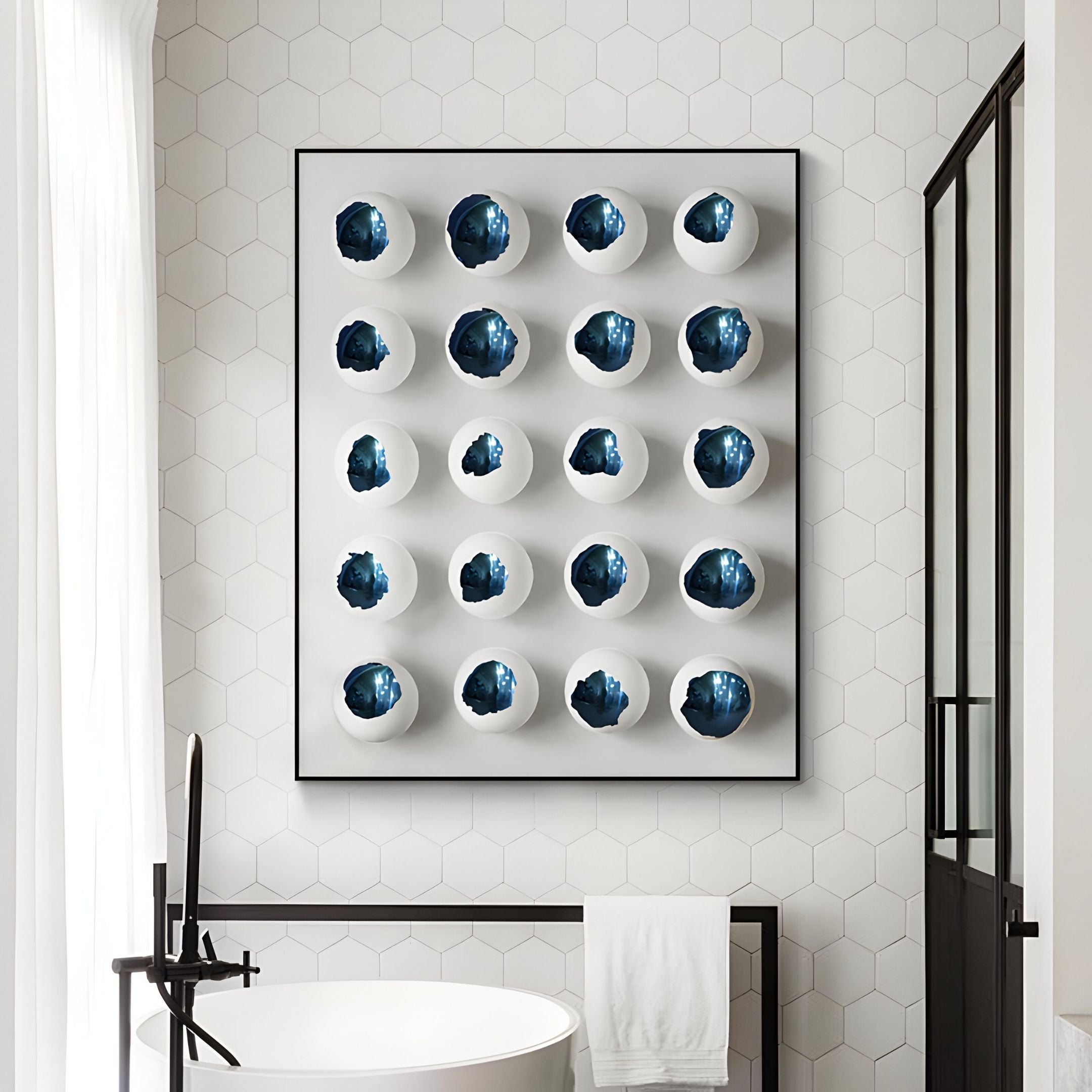 A modern bathroom with a hexagonal tile wall displays Giant Sculptures’ Orbivelle Cobalt Patch Sphere & White Panel 3D Wall Art—20 blue and white geode-like circular pieces. A towel hangs below, with a bathtub and glass shower door in view.