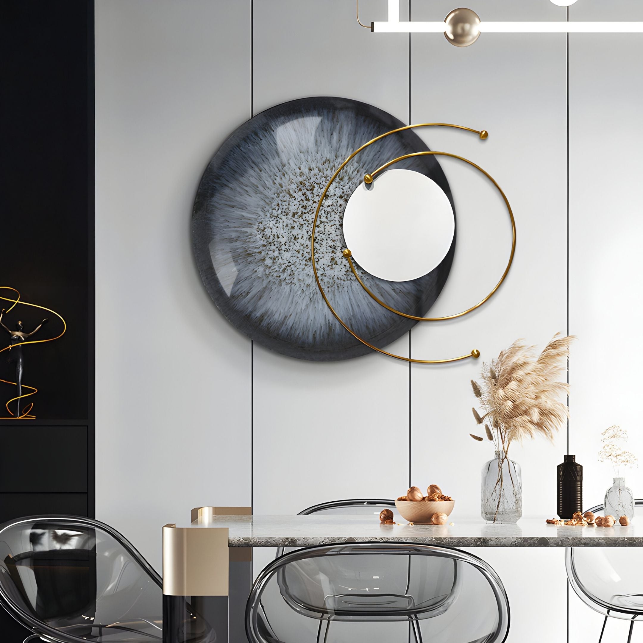 A modern dining area with a marble table, clear chairs, pampas grass, and Giant Sculptures' Aurelios Frost Grey Crystal Porcelain & Gold Orbit 3D Wall Art creates a sophisticated focal point with its layered metallic gold and gray circles and mirror accent.
