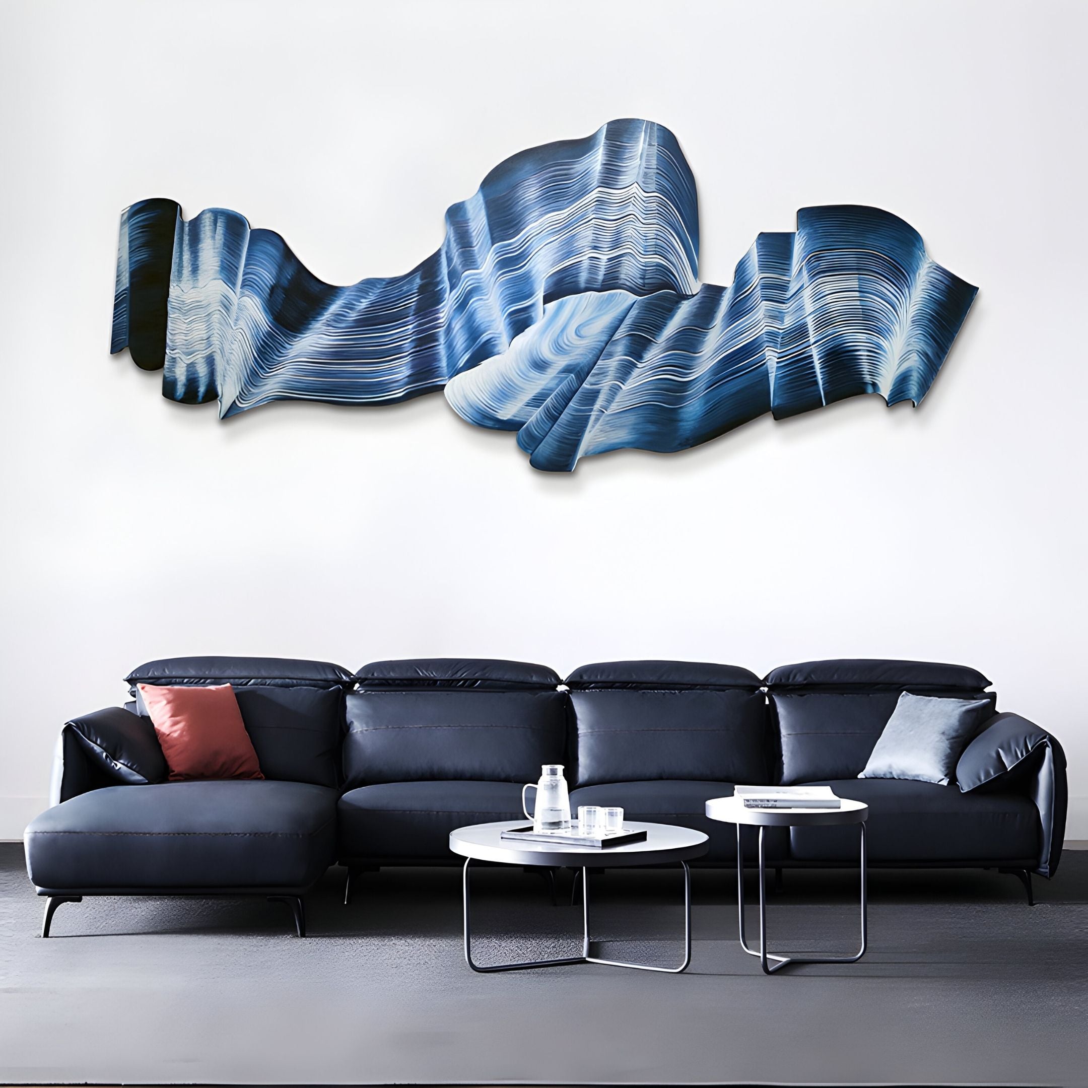 A modern living room features a dark blue sectional with red and gray pillows, two round coffee tables, and Giant Sculptures’ Vellun Wave Midnight Blue Sculptural 3D Wall Art above the couch, evoking the look of blue waves.