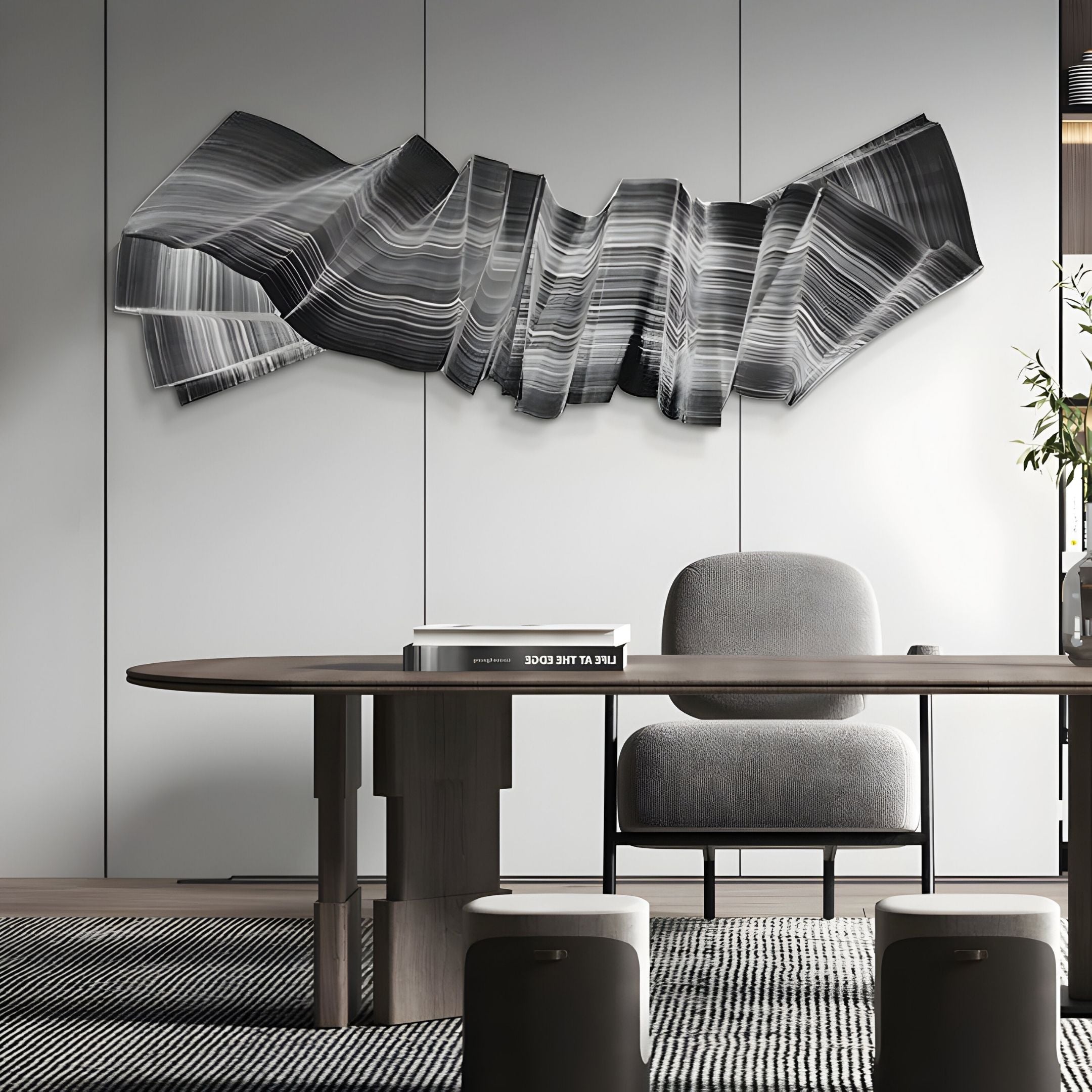 A modern office with a sleek desk, gray upholstered chair, and the Vellun Wave Charcoal Grey Sculptural 3D Wall Art by Giant Sculptures on a light-paneled wall. Minimalist decor features books, a plant, and a patterned rug for effortless style.