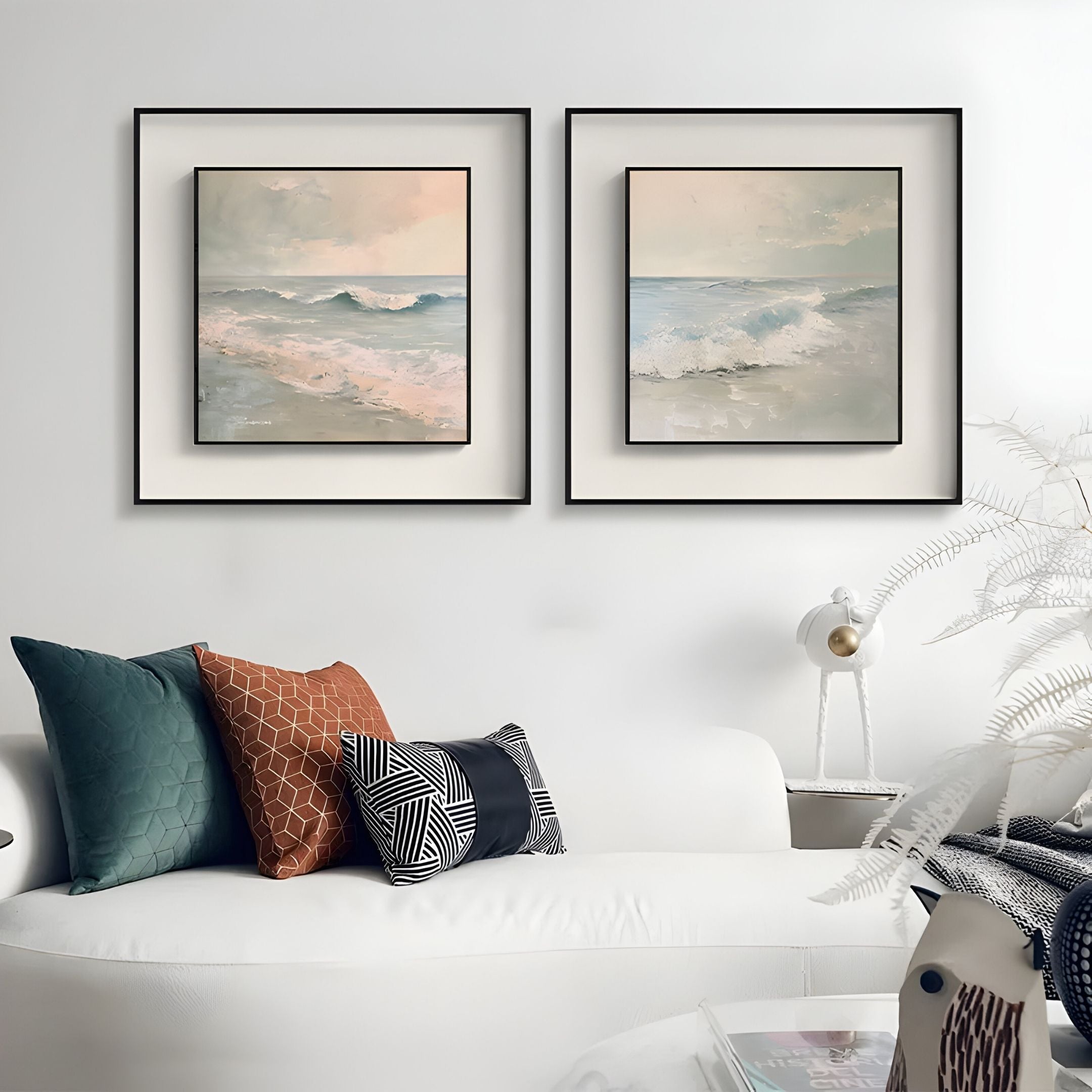 A modern living room with a white sofa, colorful cushions, a white lamp, and the Giant Sculptures Tidalume I Soft Dawn Shoreline Double Framed Wall Art above the couch. A decorative plant sits nearby.
