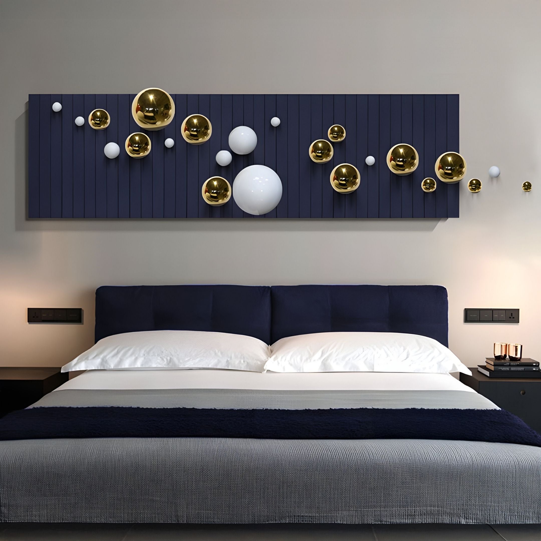 A modern bedroom features a dark blue bed with white bedding and Giant Sculptures’ Orbivance Navy, Gold & White Sphere Panel 3D Wall Art above the bed. Nightstands with lamps are placed on either side.