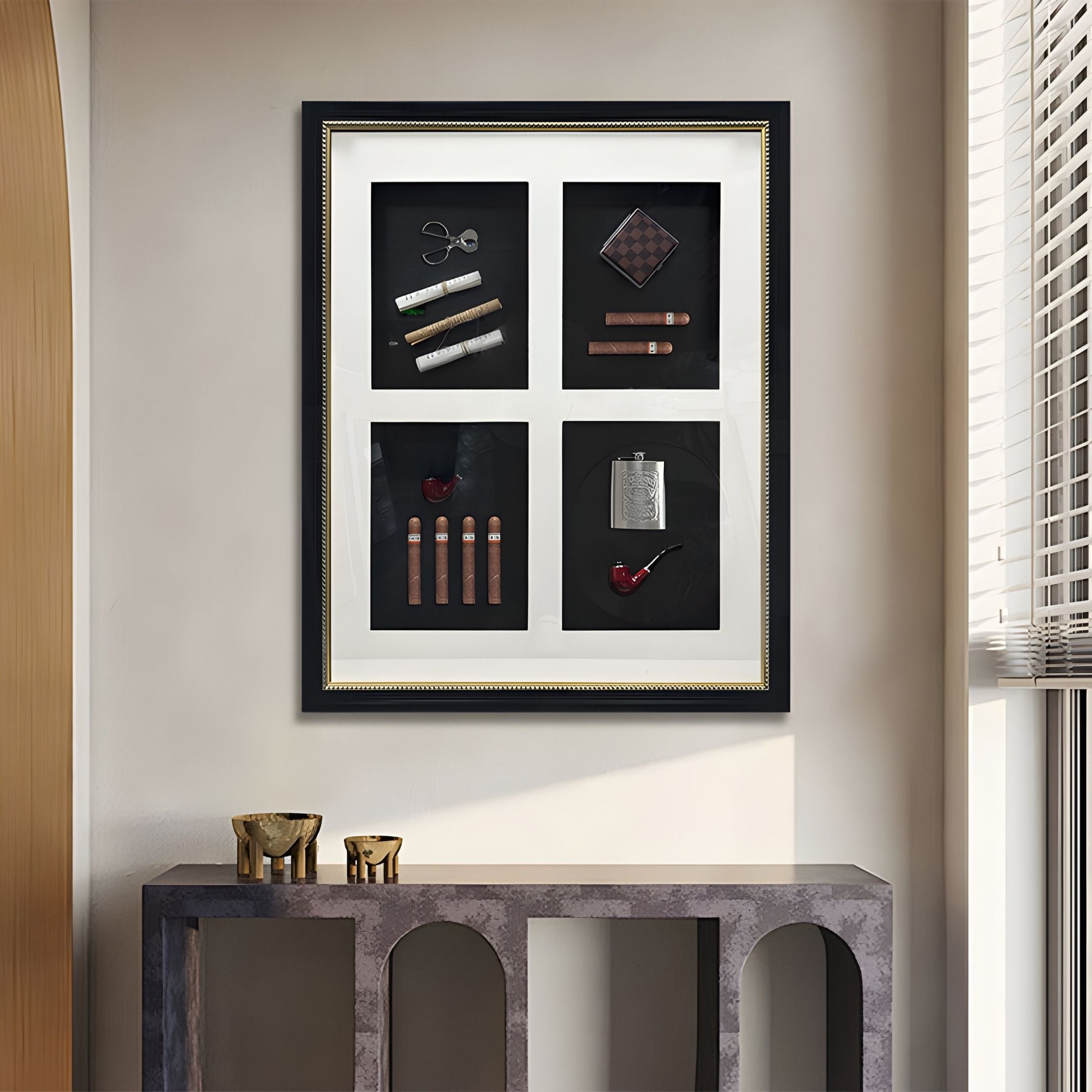 The Cavendrix II Gentleman Cigar Set Curated Framed Wall Art by Giant Sculptures features cigars, pipe, flask, cutters, and lighter in four sections within an Italian-style frame, displayed above a modern gray console table with sunlit blinds.