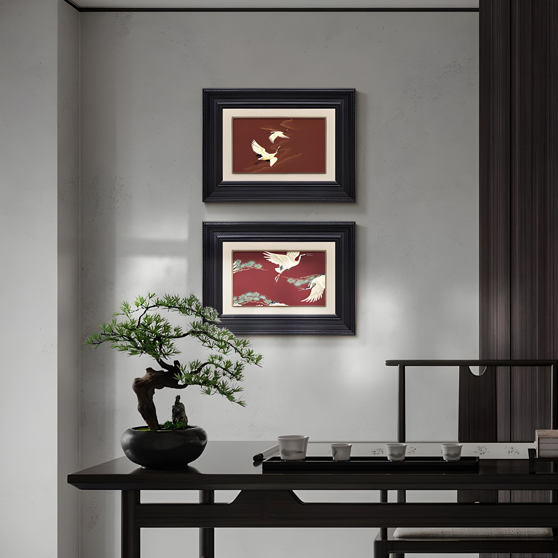 A minimalist room features a bonsai, tea set, and Kansora Heritage Crane Flight 2-Set Framed Wall Art by Giant Sculptures on a gray wall, creating a serene, Asian-inspired interior with timeless decor.