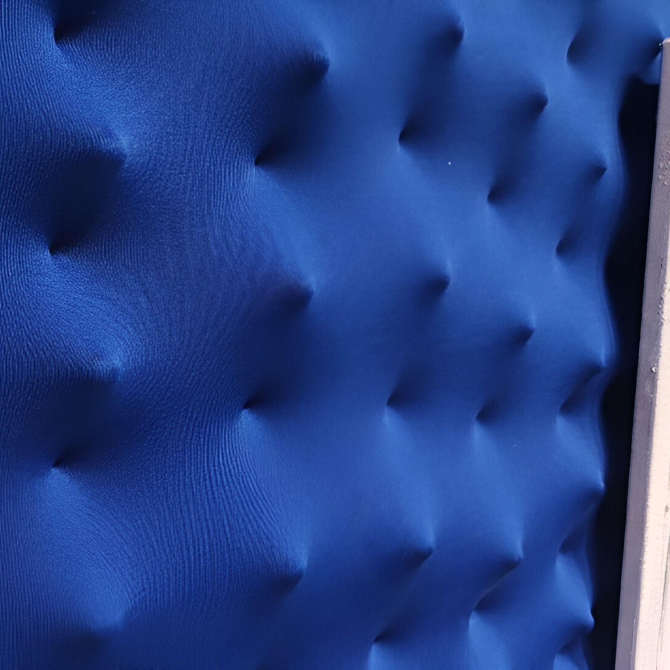 Close-up of Loftera Blue Sculpted Fabric & Abstract Canvas 3D Wall Art by Giant Sculptures, featuring a blue textured surface with raised, rounded bumps in a grid for a soft, padded look reminiscent of sculpted fabric wall art.