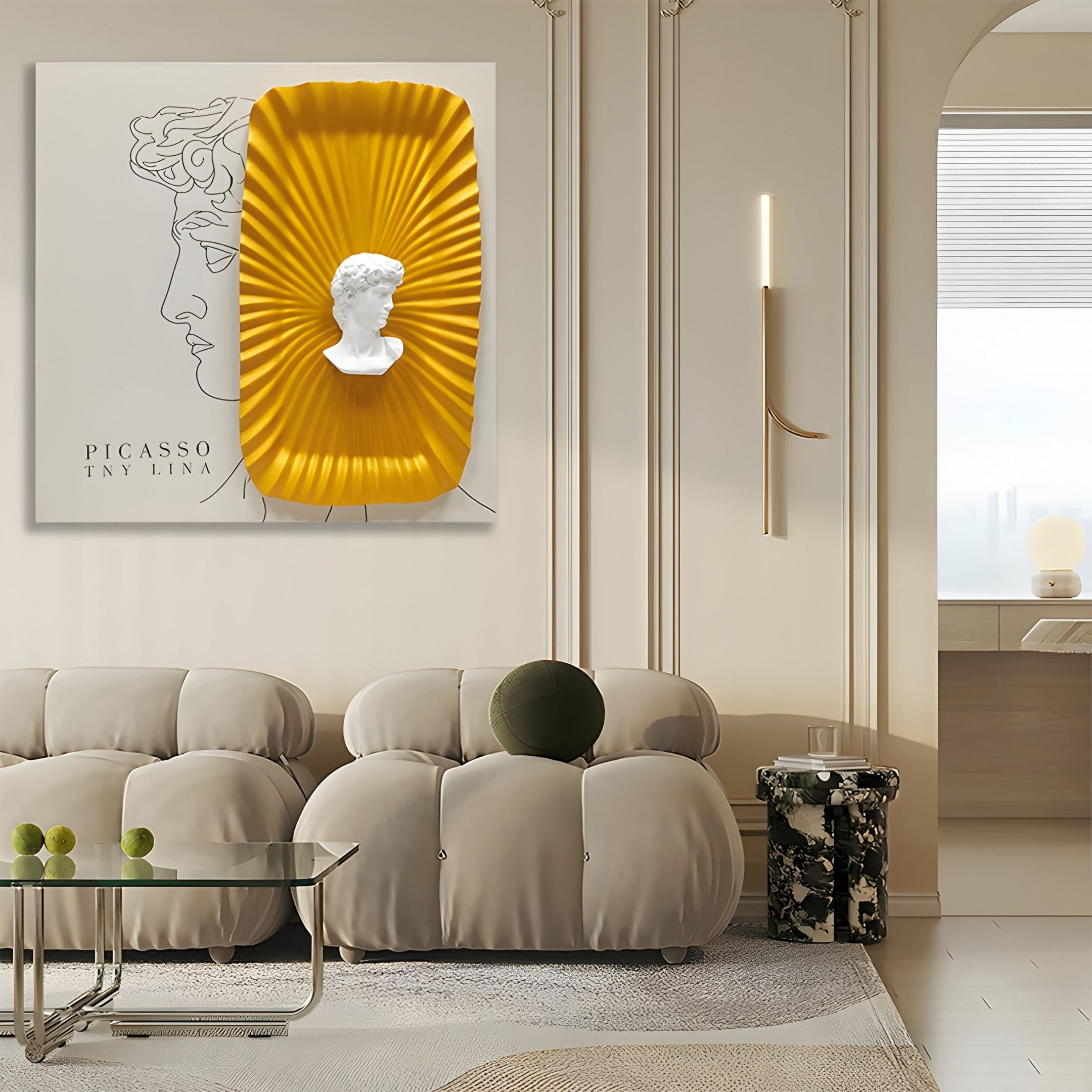 A modern living room with light beige sofas, a glass coffee table, and the Castellune Gold Radiant Classical Bust 3D Wall Art by Giant Sculptures as striking décor. A decorative side table and large window complete the elegant, minimalist space.