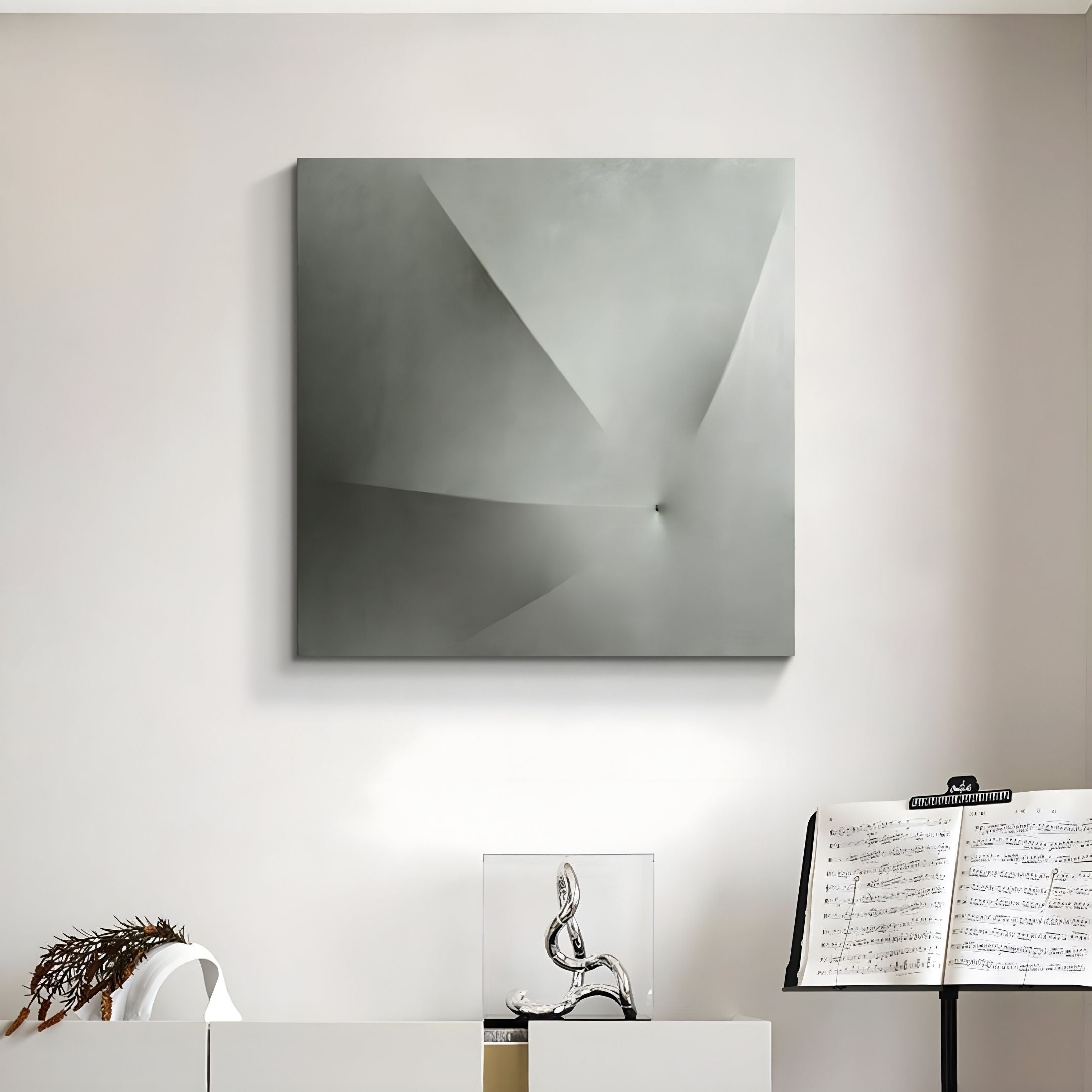 The Veylora Mist Silver Folded Texture Fabric 3D Wall Art by Giant Sculptures hangs above a shelf with a silver sculpture, plant, and music stand with sheet music, creating a sculptural minimalist vibe.