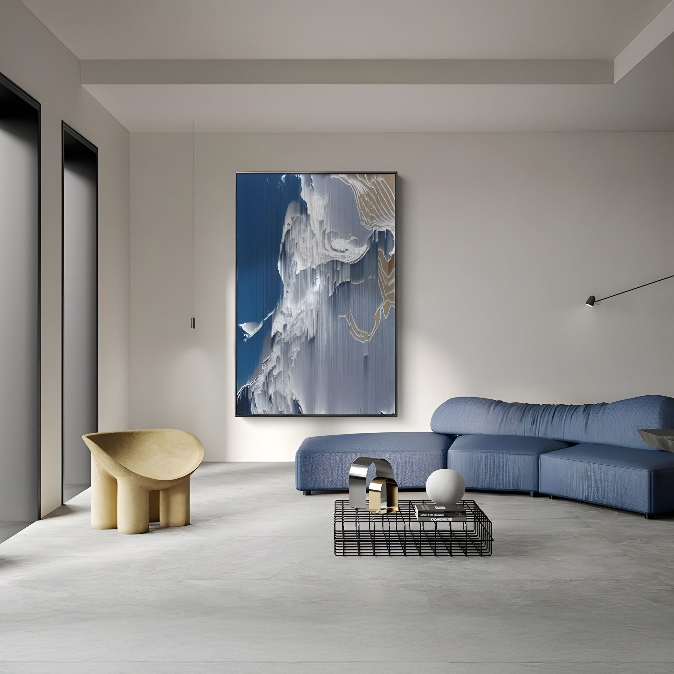 A modern living room features a blue sectional sofa, the Aerolune Blue & White Vertical Gradient Rope 3D Wall Art by Giant Sculptures, a unique beige chair, a wire-frame coffee table with decor, large windows, and minimalist style.