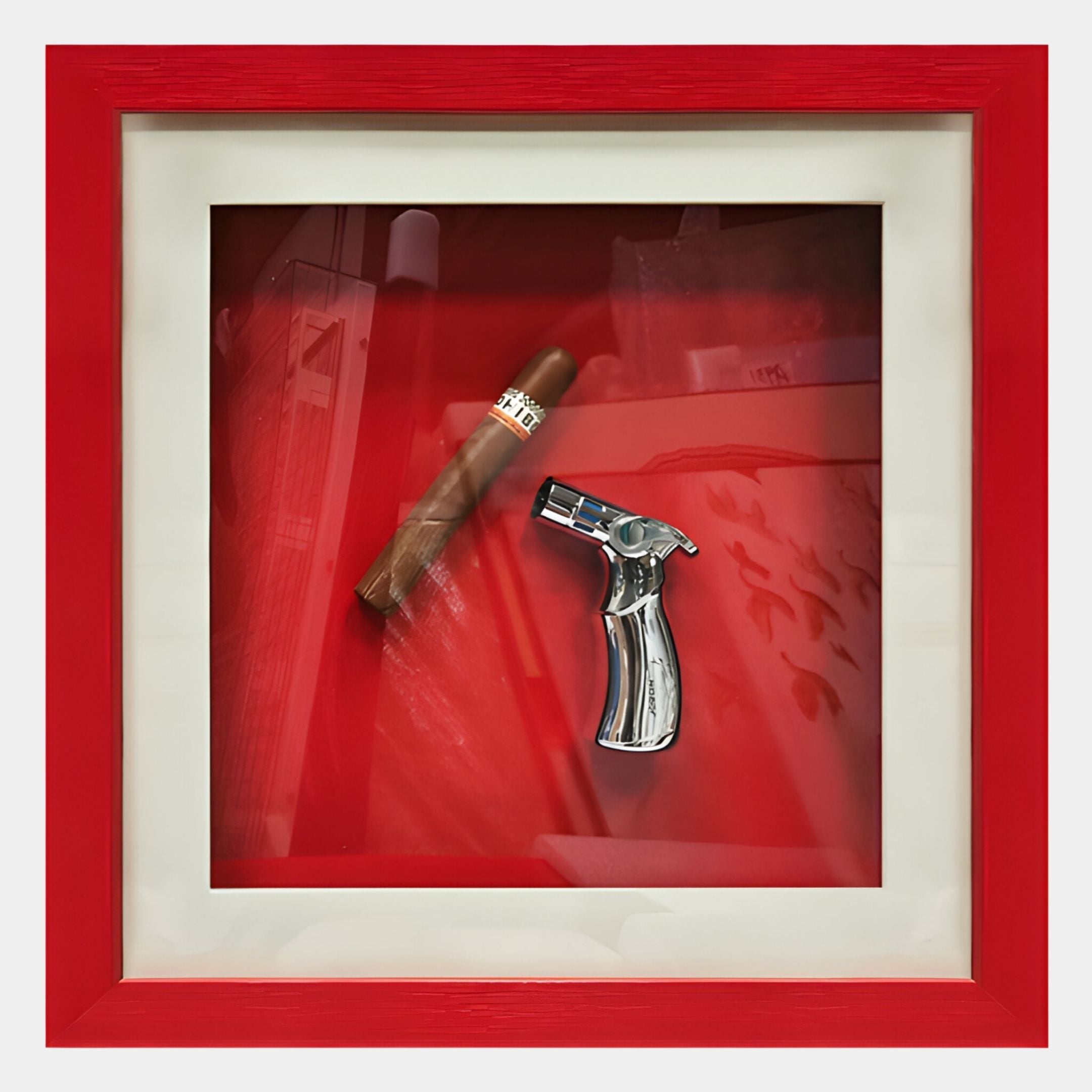 The Cavendro Single Cigar & Torch Lighter Framed Wall Art by Giant Sculptures showcases a cigar and silver torch lighter on a red background with white mat, red border, and glass reflections for added depth.