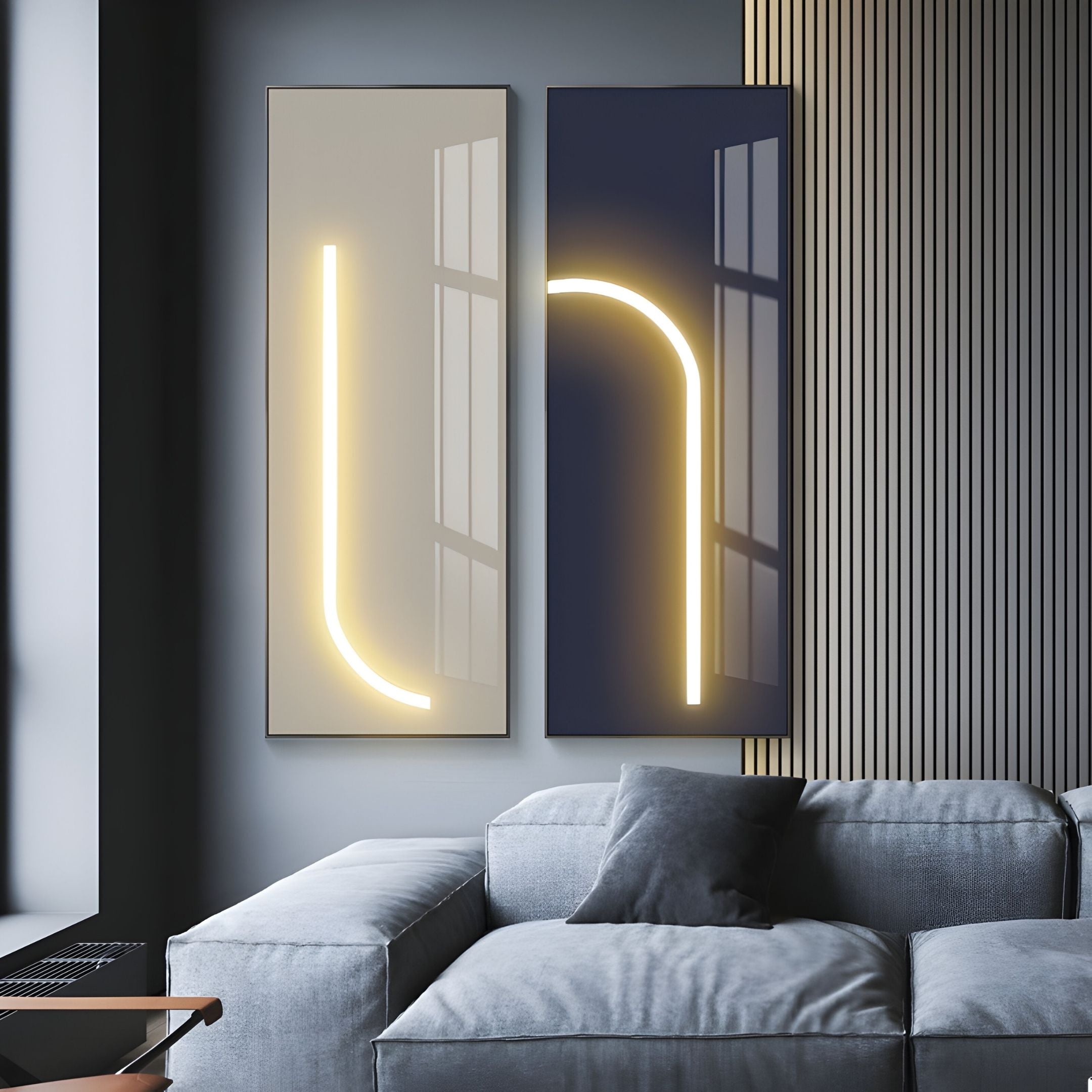 Two Luminarch Beige Line LED Minimalist Wall Art pieces by Giant Sculptures with glowing curved lights hang above a modern gray sectional. Sunlight from a window highlights their ambient LED glow and nearby slatted paneling.