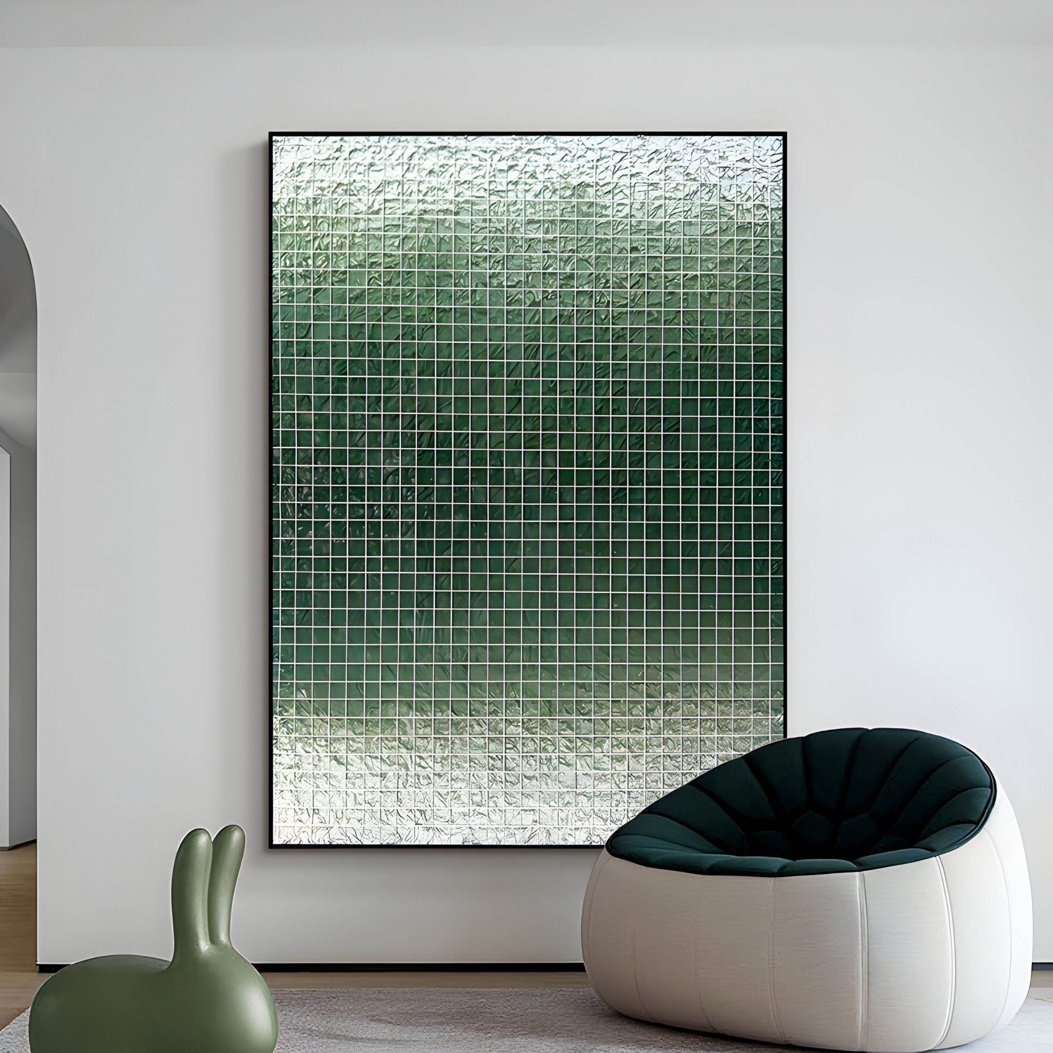 A modern minimalist room featuring Giant Sculptures' Gridelle Forest Fade Gradient Grid 3D Paper Wall Art in green tones, a round dark green cushioned chair, and a small green bunny-shaped decor piece on a light floor.