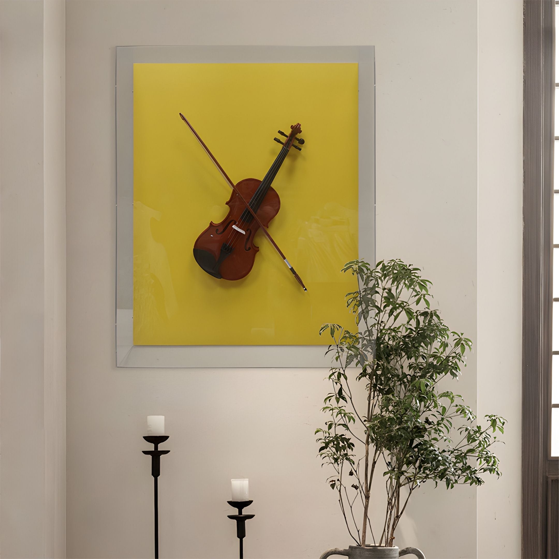 The Archetto Yellow Violin Acrylic Framed 3D Wall Art by Giant Sculptures features a violin and bow on a bold yellow background, making striking modern wall decor above black candle holders and a leafy green potted plant.