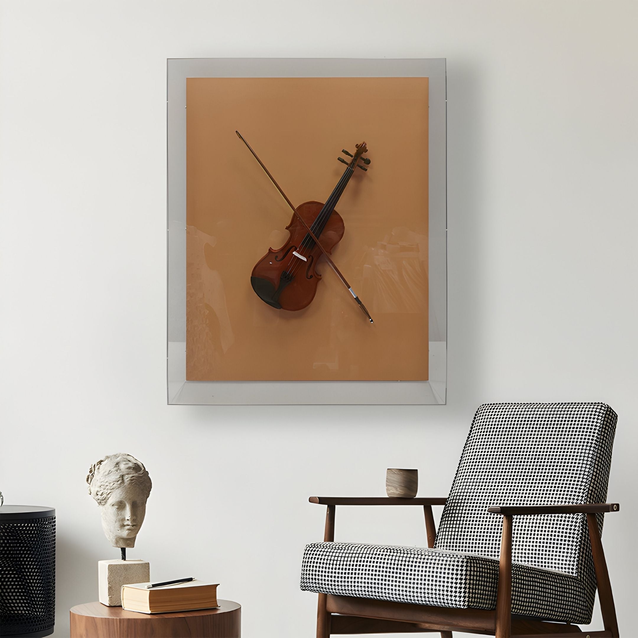 The Archetto Terra Violin Acrylic Framed 3D Wall Art by Giant Sculptures hangs above a patterned armchair. Nearby, a statue head, black cylinder, and books on a wooden table complete the artistic scene.