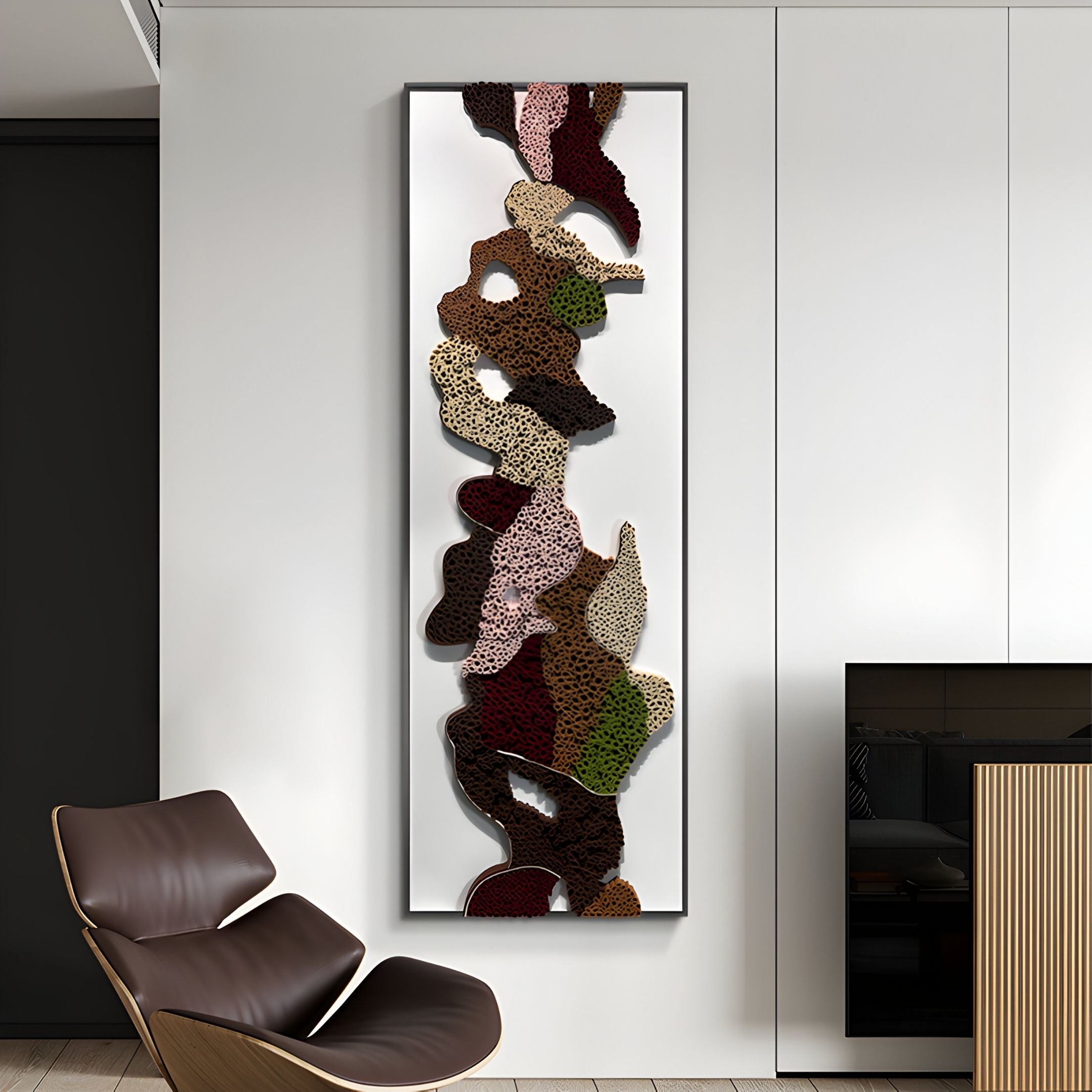 The Verdurelle Earth Layered Flow Felt 3D Wall Art by Giant Sculptures displays textured shapes in brown, beige, pink, burgundy, and green on a white wall in a modern room with a leather chair and fireplace.